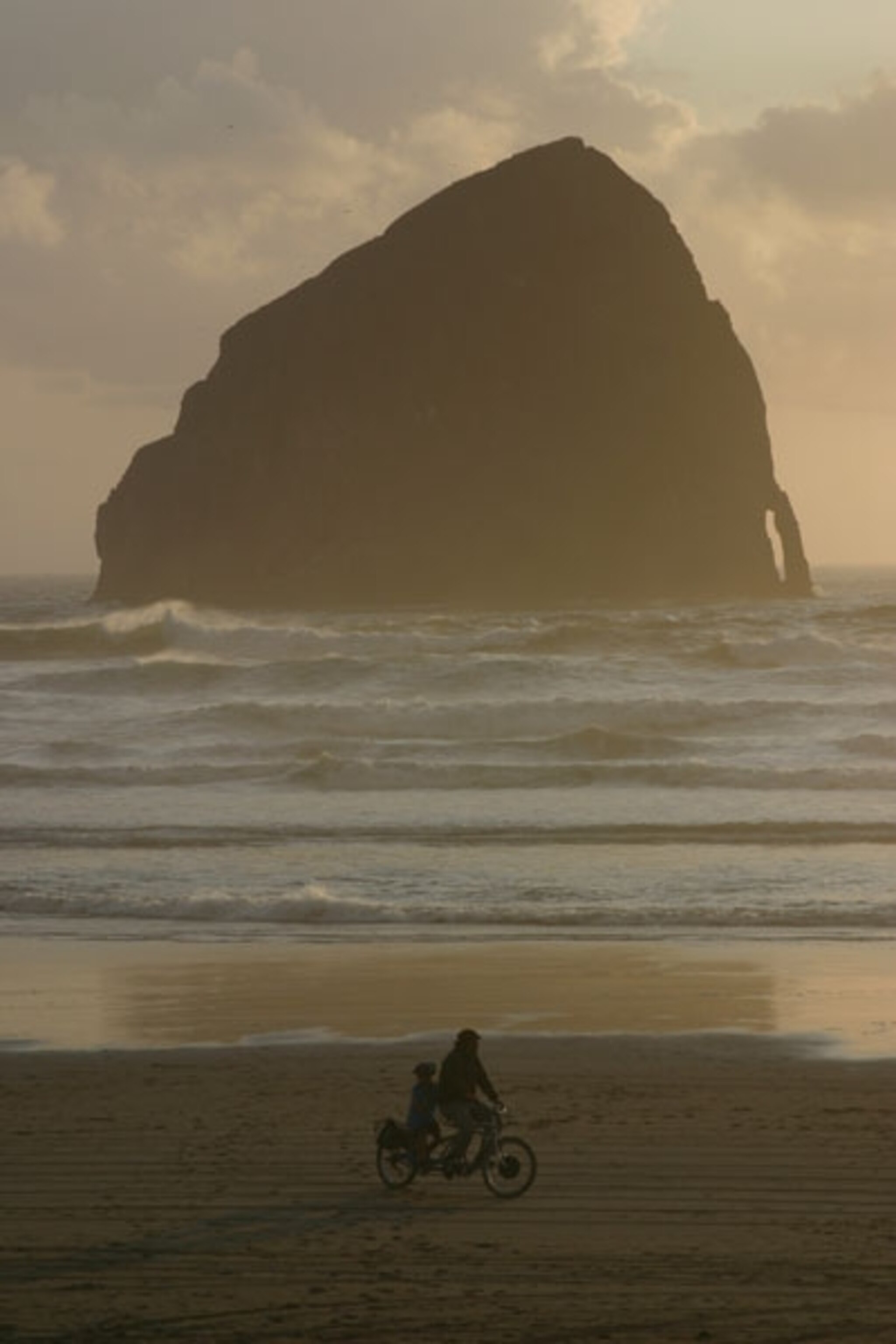 Two people riding a bike on the beach in Oregon