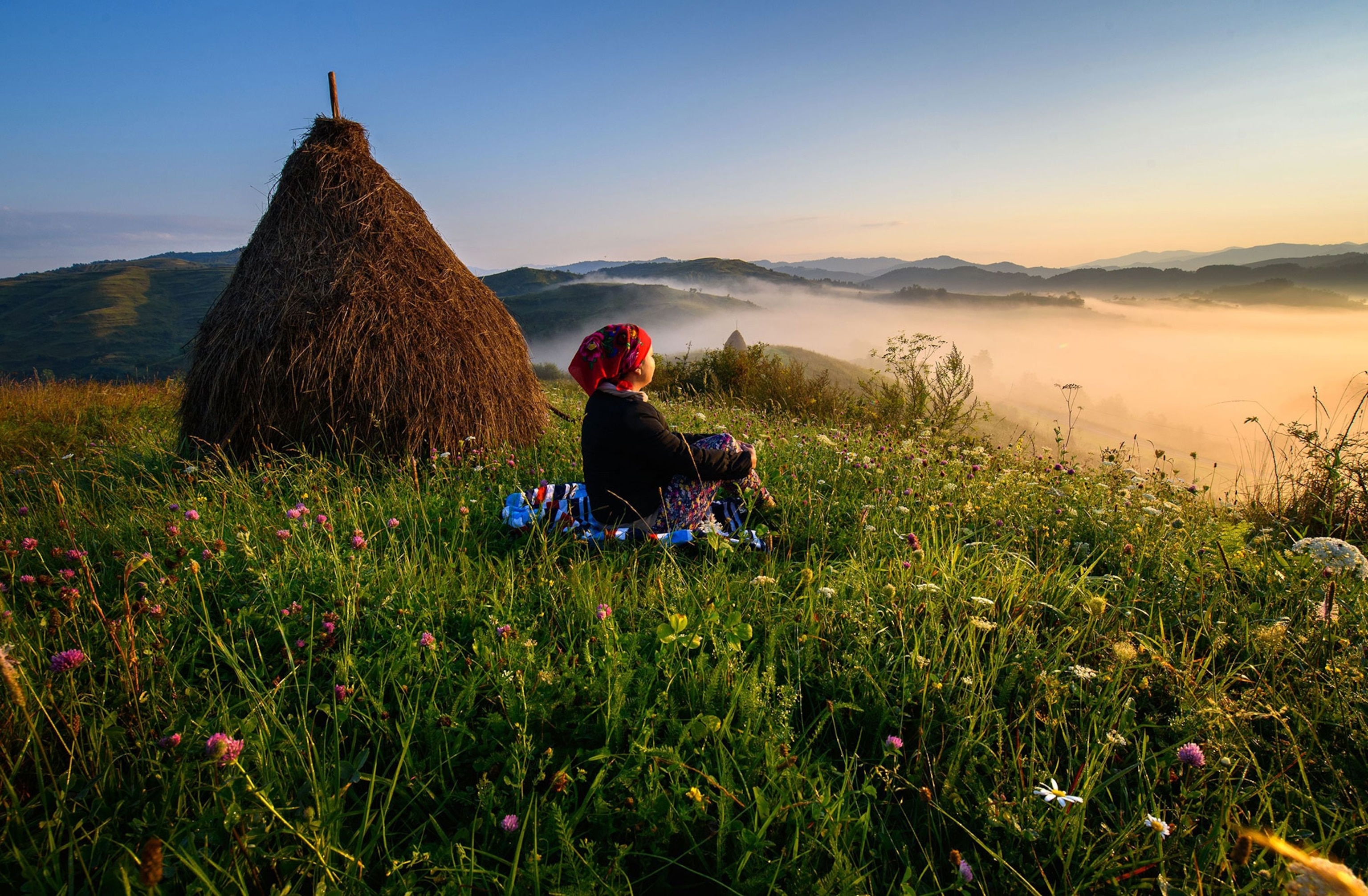 a woman sitting next to a haystack