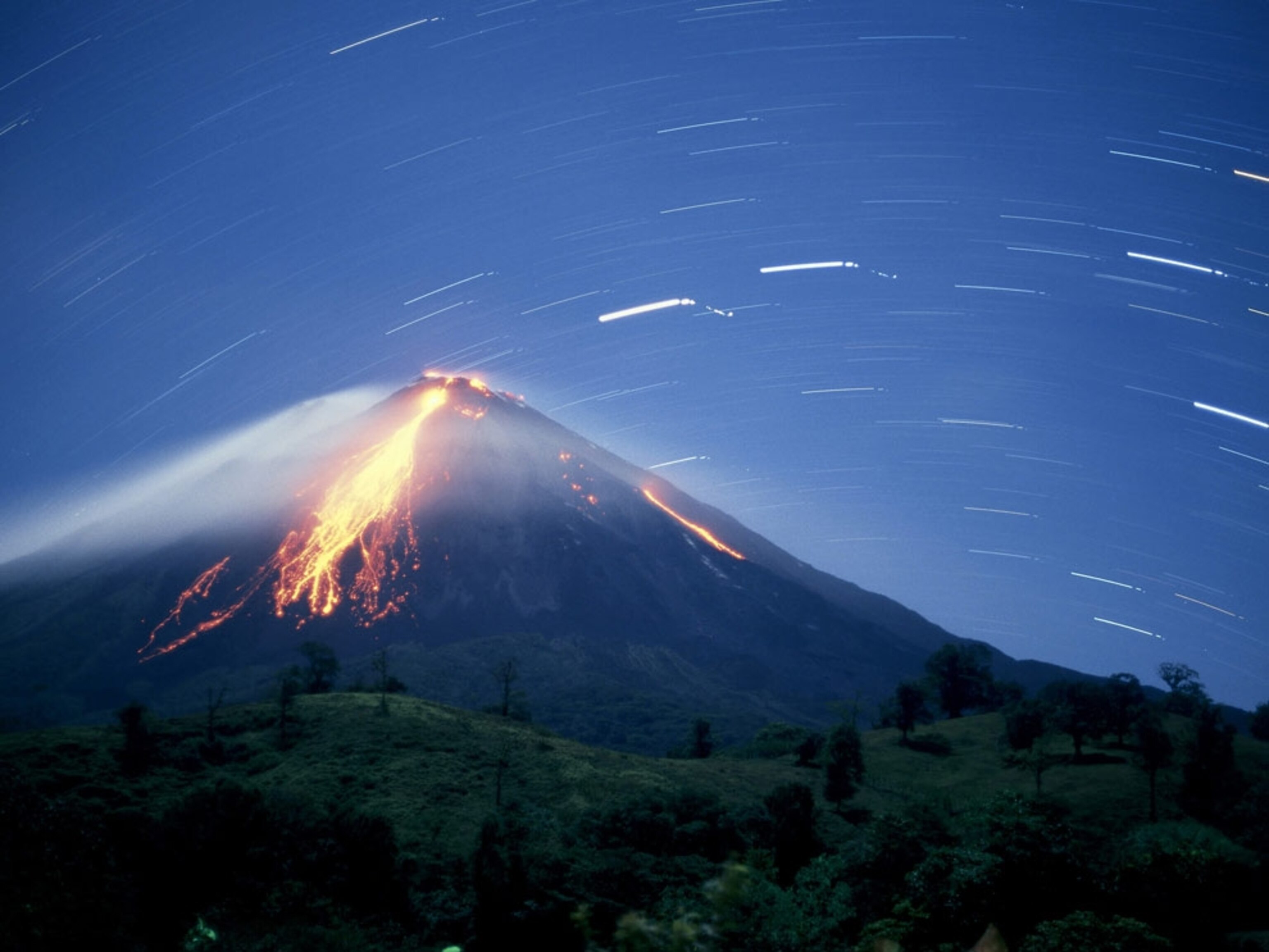 Volcanic eruption amid verdant hills