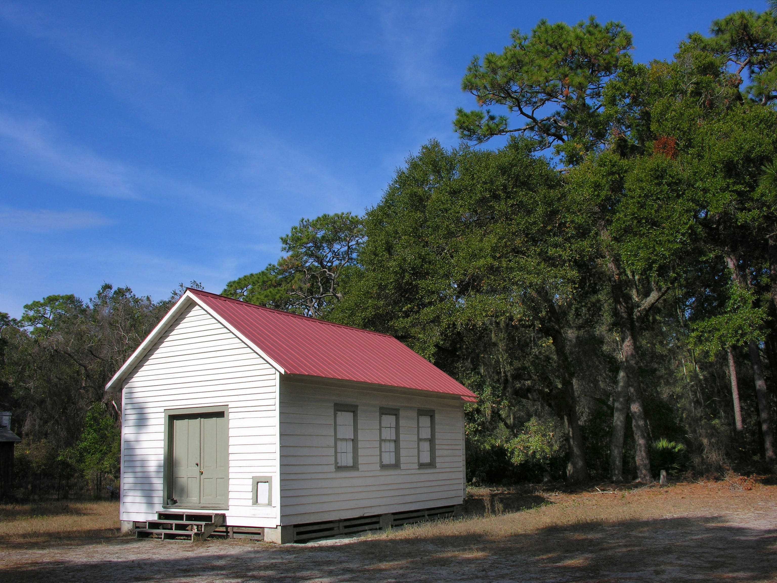 A white chapel with a red roof stands as the sole building amongst a forest
