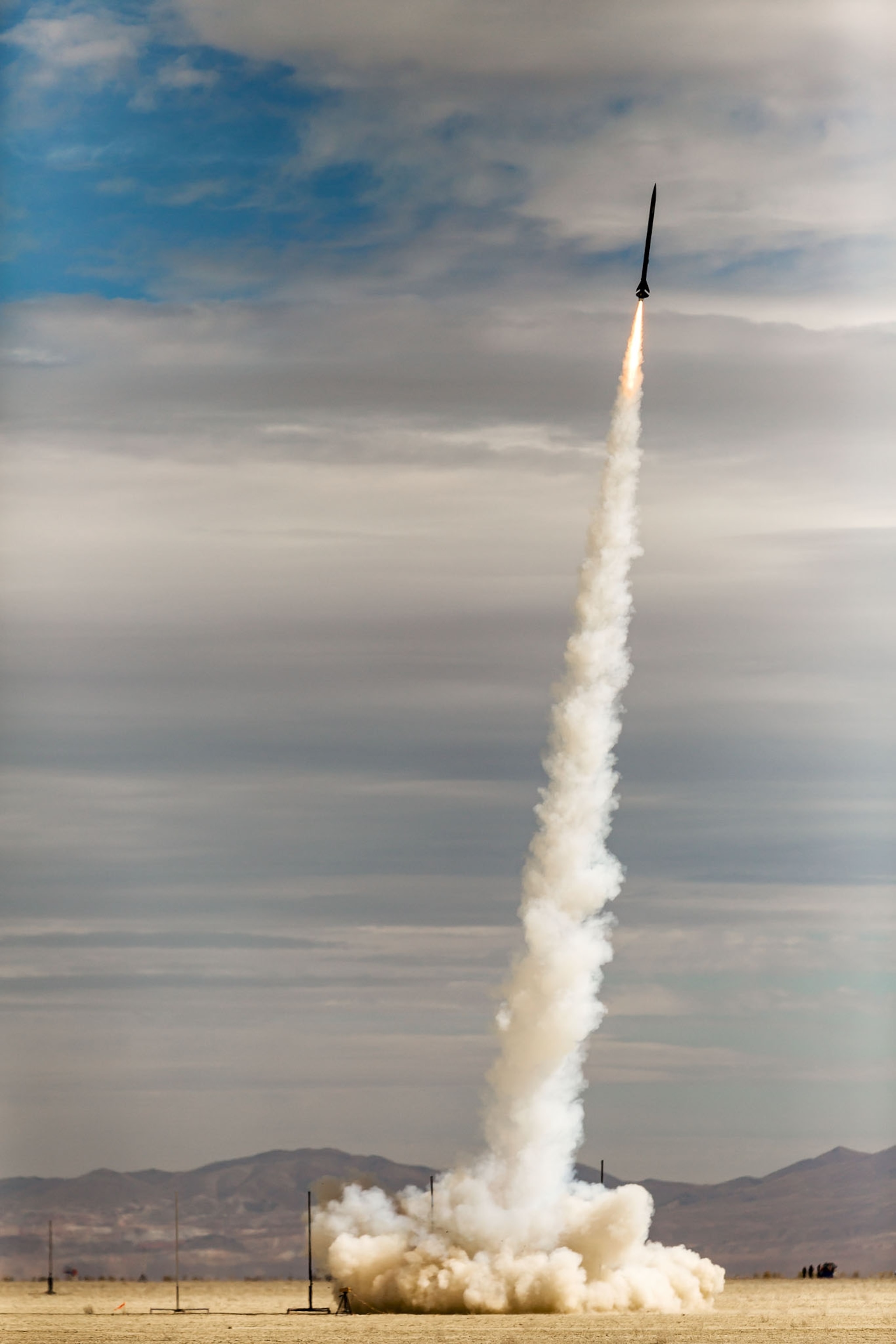 a rocket launched into the air leaving a white smokey trail in the desert