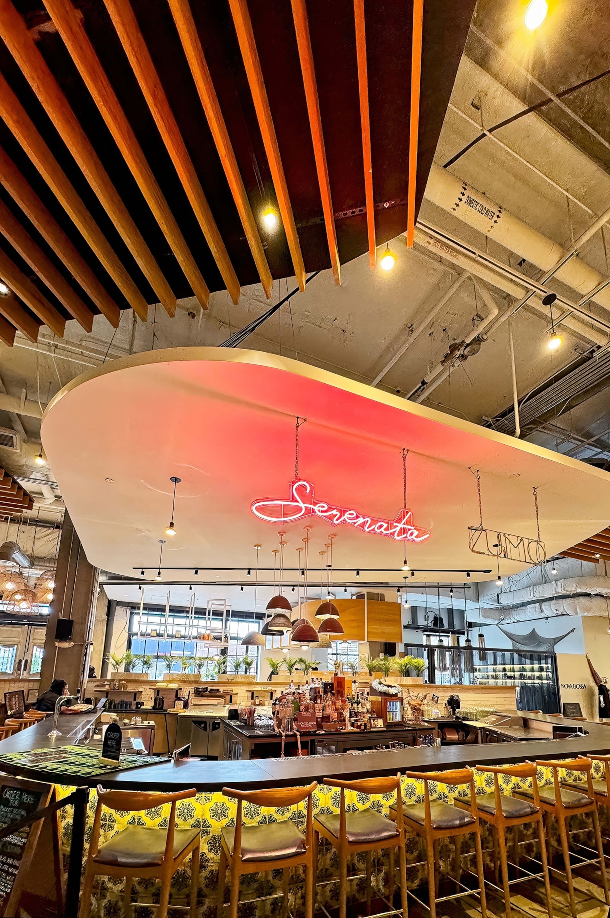 A cocktail bar has a neon sign inside a building.