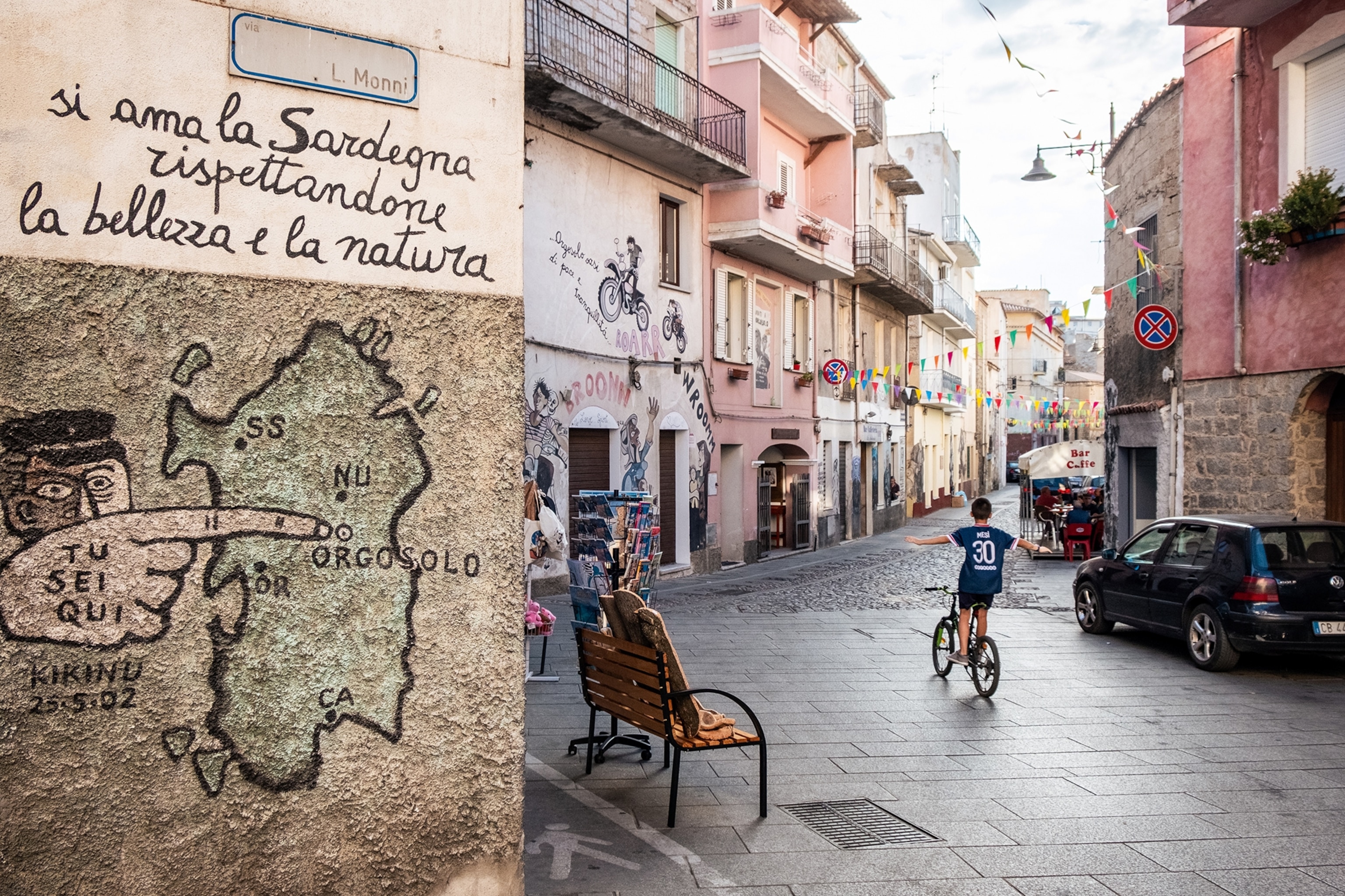 Graffiti on a wall, in the background a boy cycling down the street.