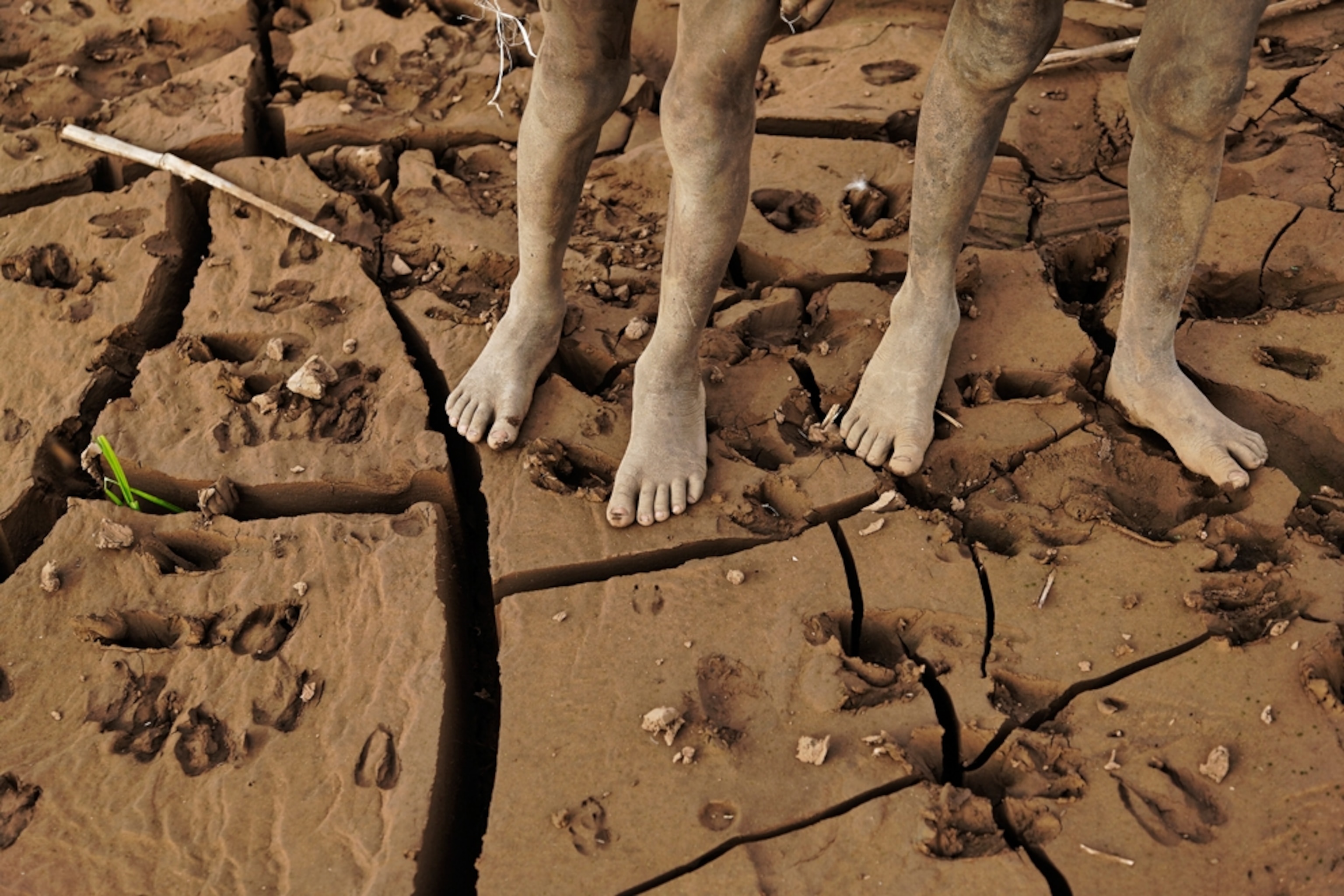 Kara boys standing on a mud-caked riverbank, Ethiopia
