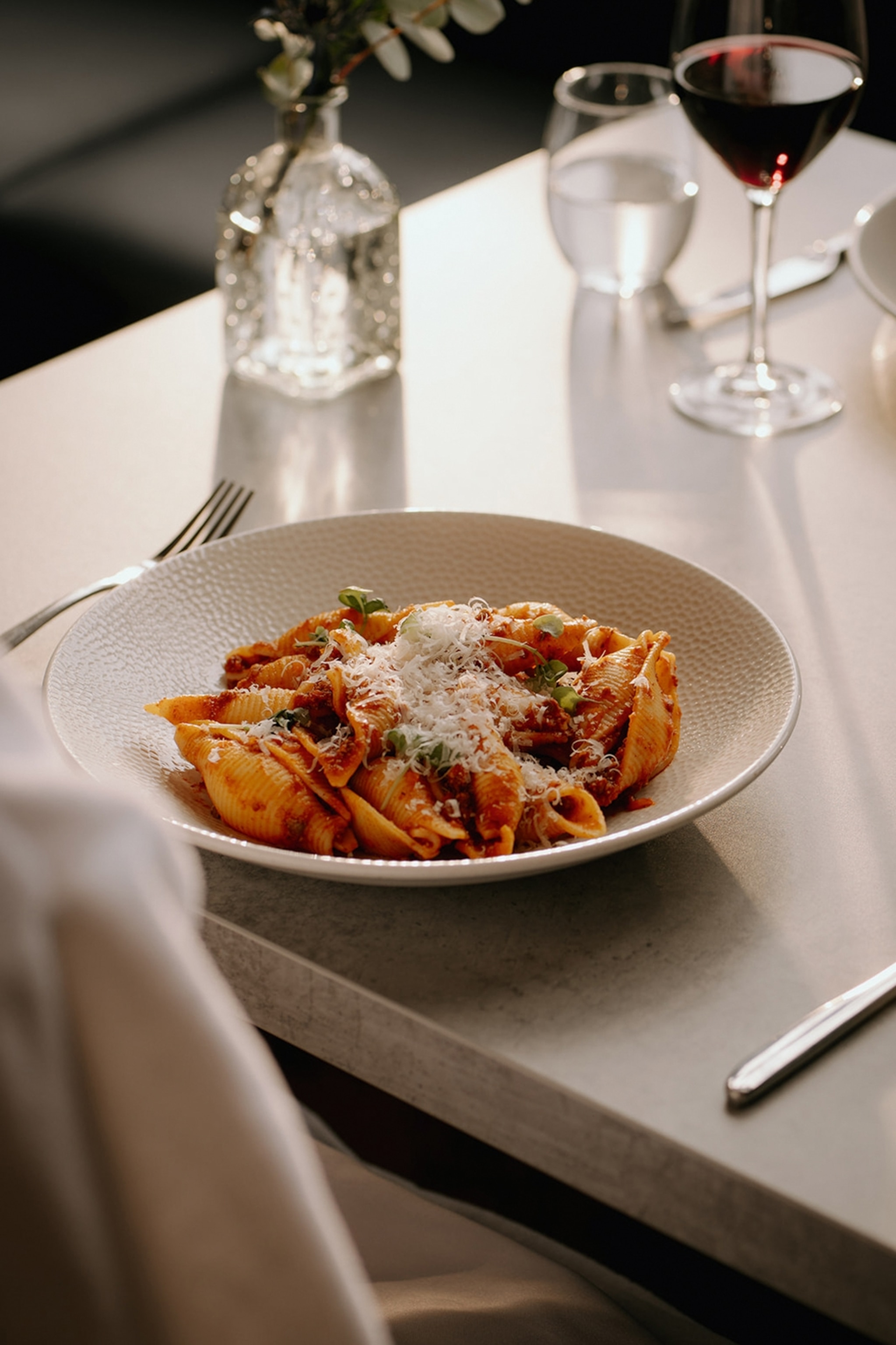 A plate of tomato pasta in an elevated dining setting.