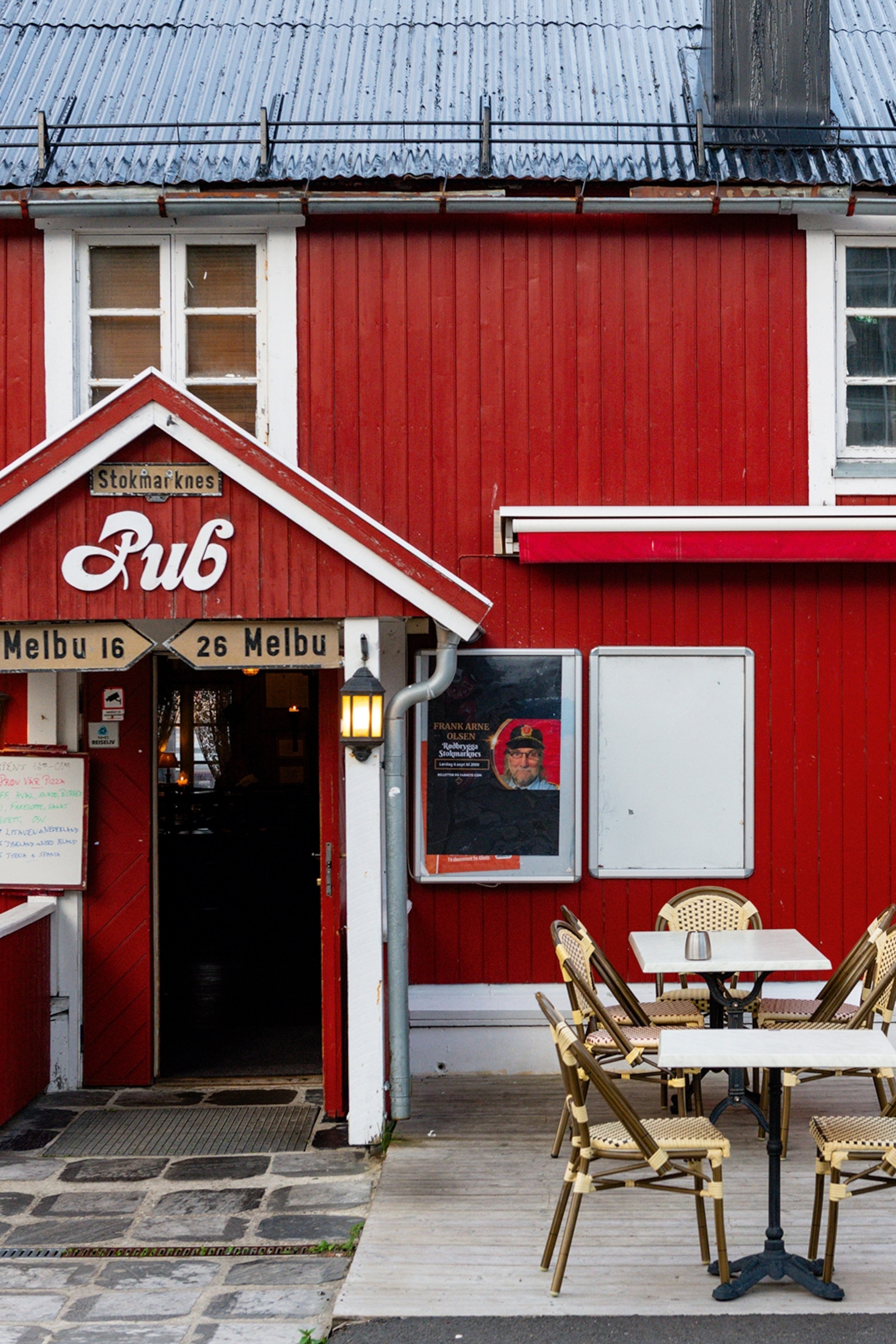 The exterior of an Norwegian block hut functioning as a pub with outdoor seating.