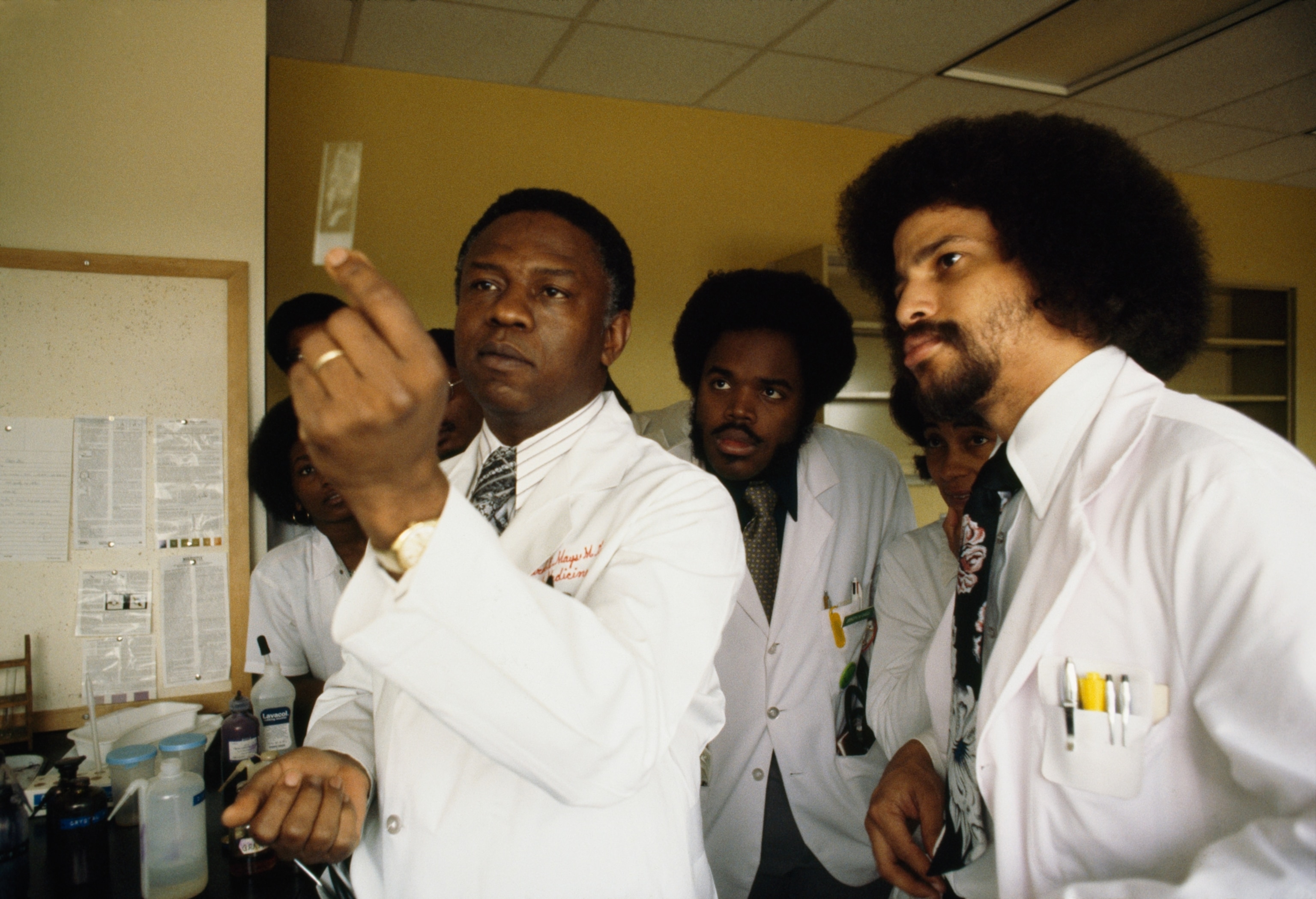 A doctor examines a blood specimen with his students at a medical college