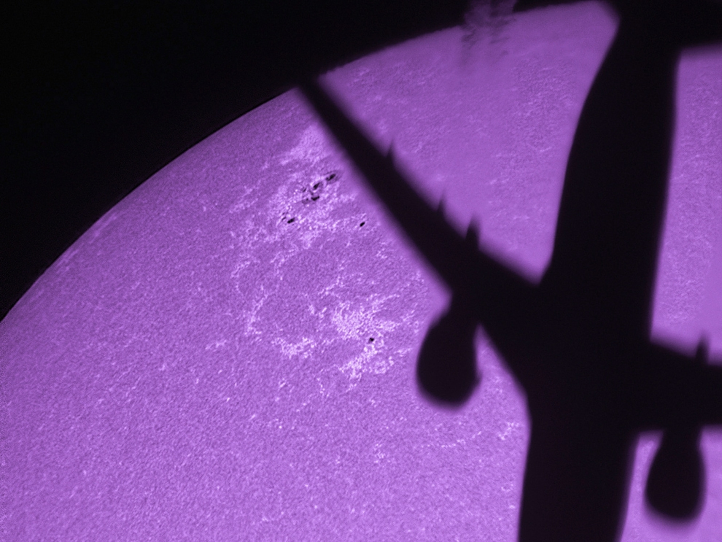an airplane silhouetted against a purple sun.