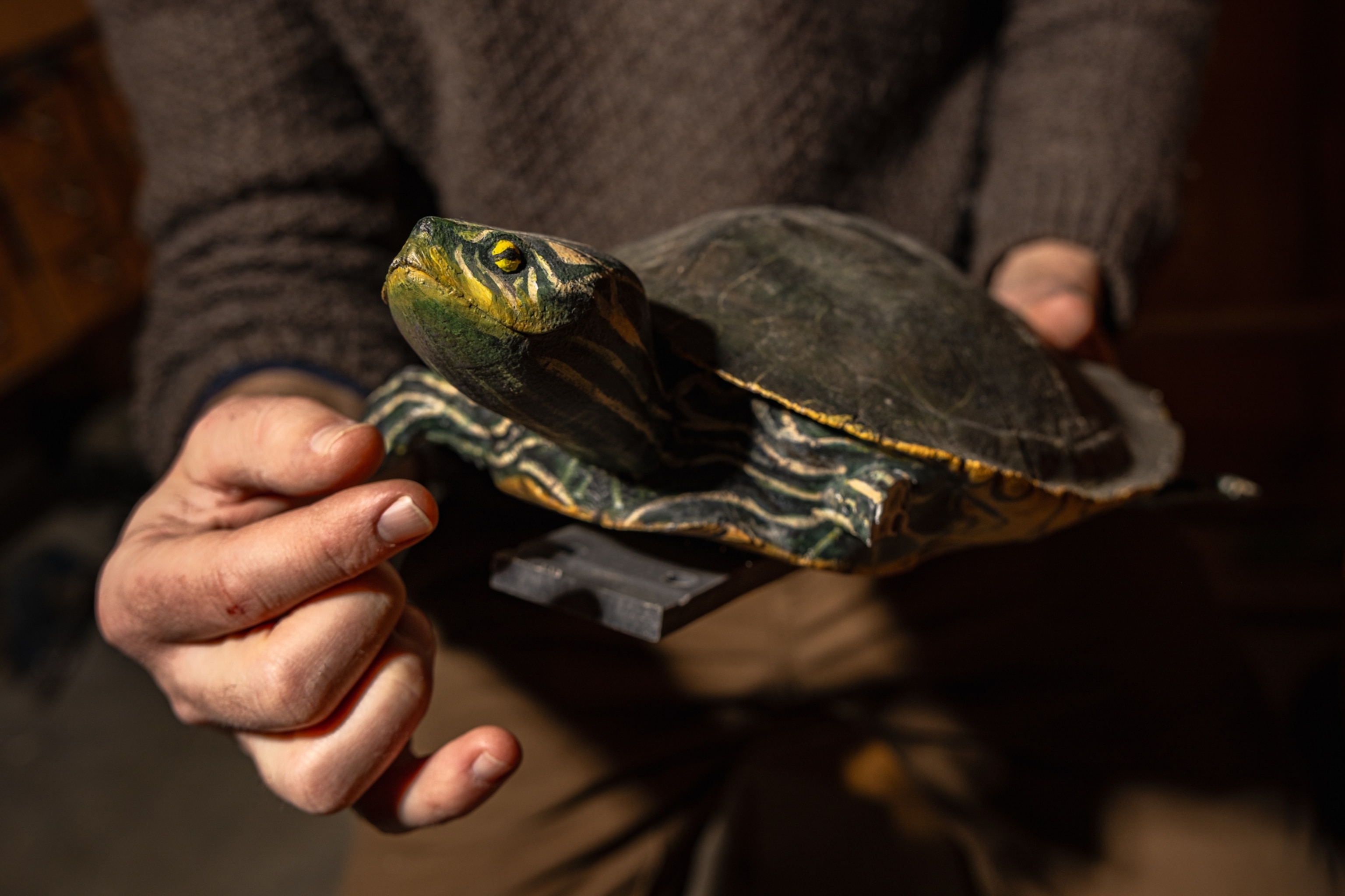 An artificial turtle with green body with yellow likes and a dark grey shell.