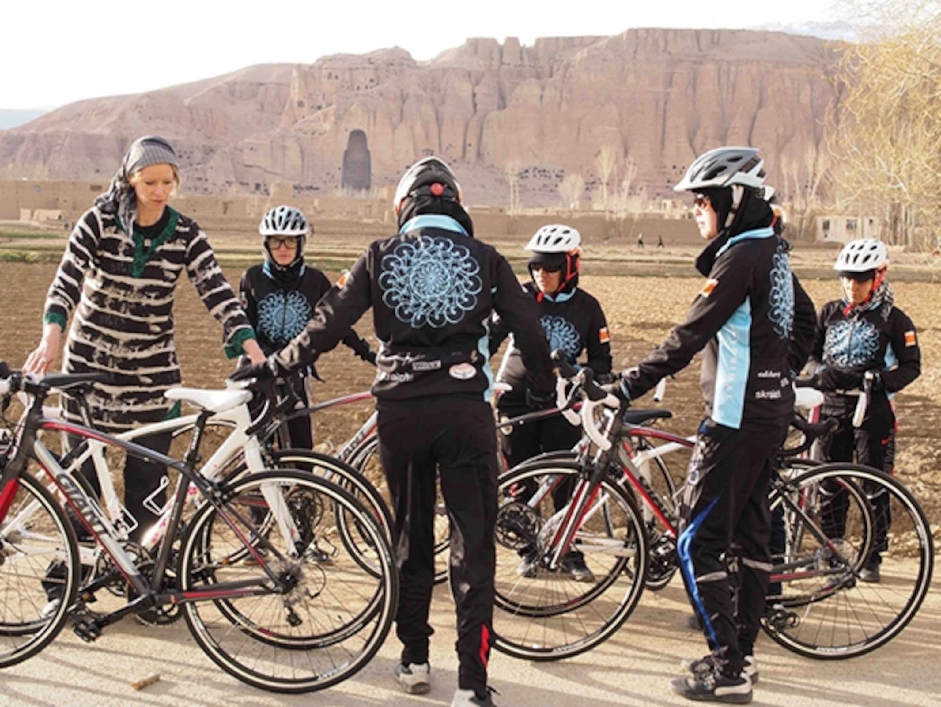 the women’s Afghan cycling team preparing for a training ride in front of the Buddha niches in Bamian, Afghanistan.