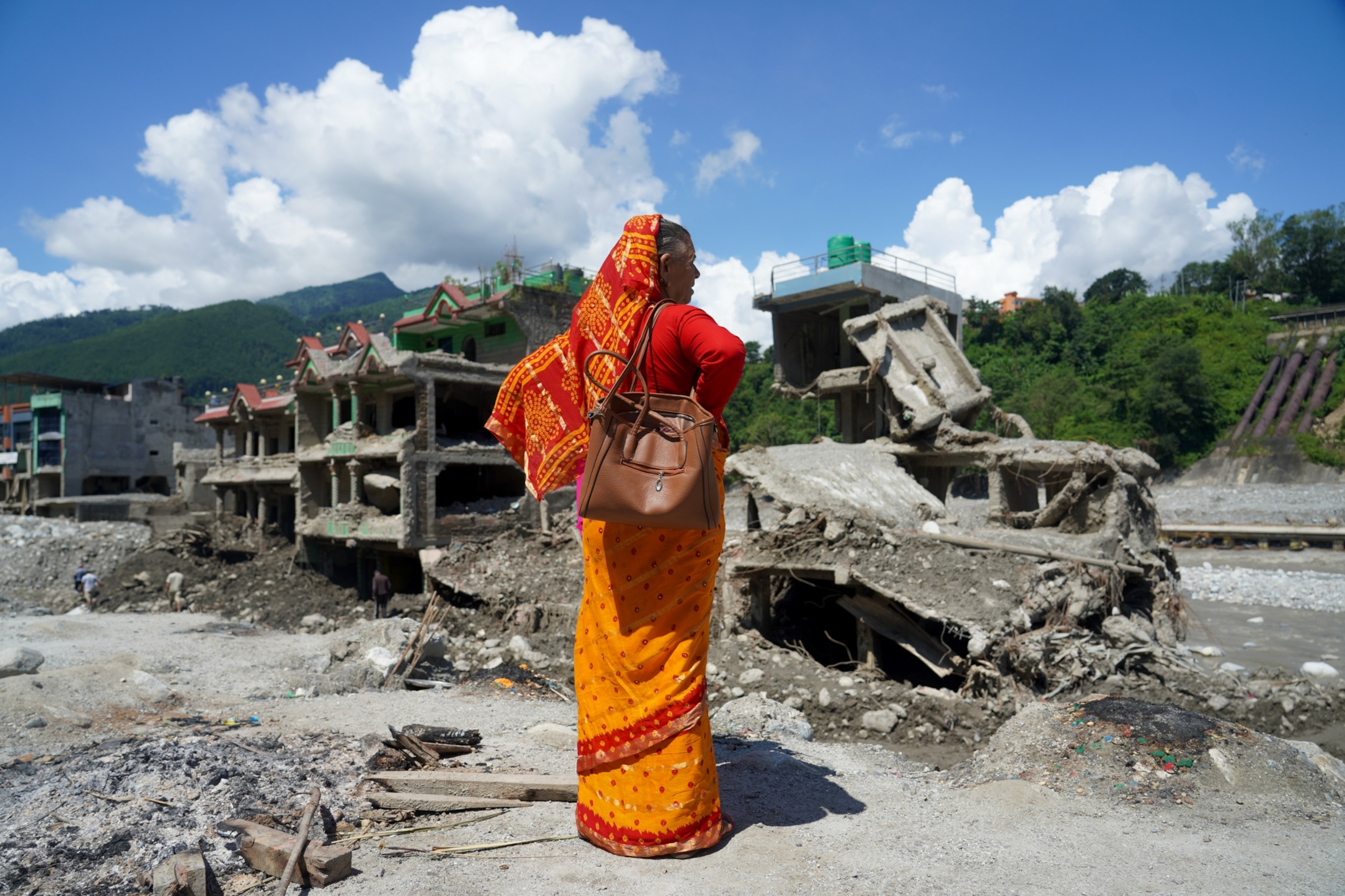 A woman stands near homes damaged by flash floods in Dhunge Bazar, Nuwakot district, Nepal.
