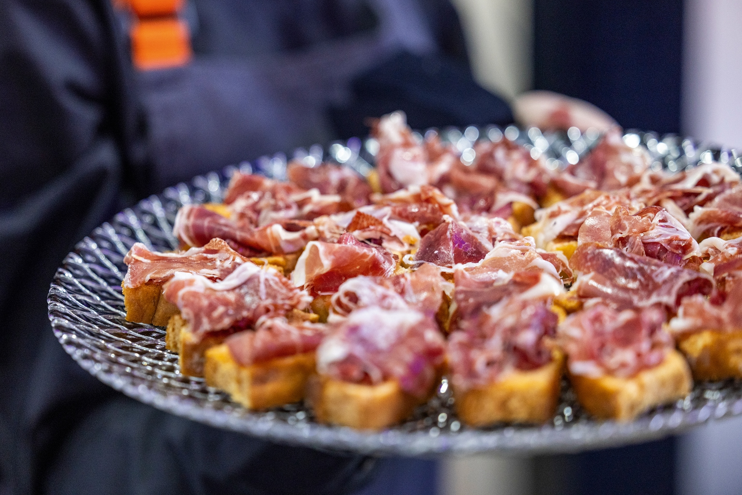 A close-up shot of a plate of jamón ibérico on top of sliced bread pieces.