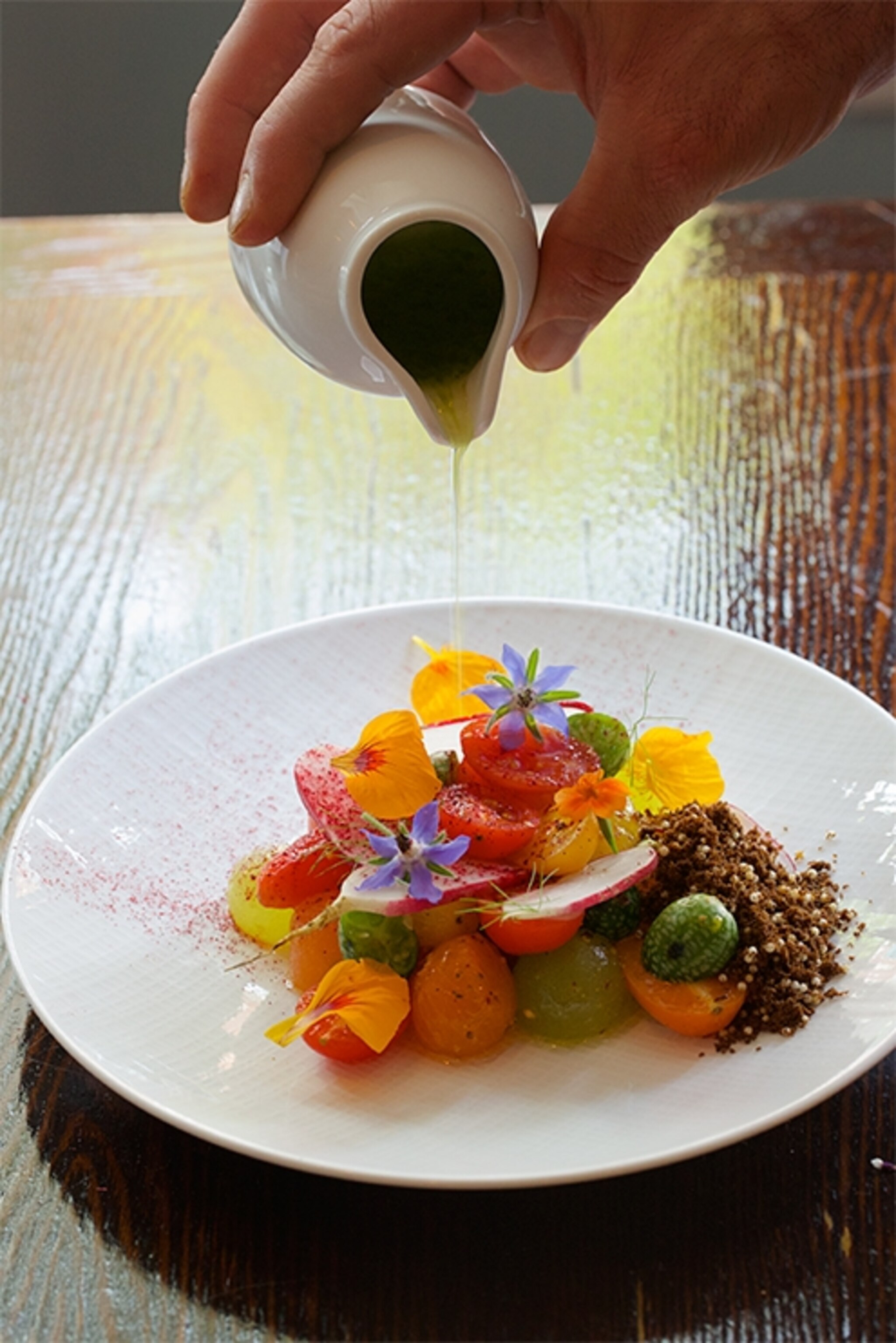 chef Christopher Kearse pouring vinaigrette over a dish at Will in Philadelphia