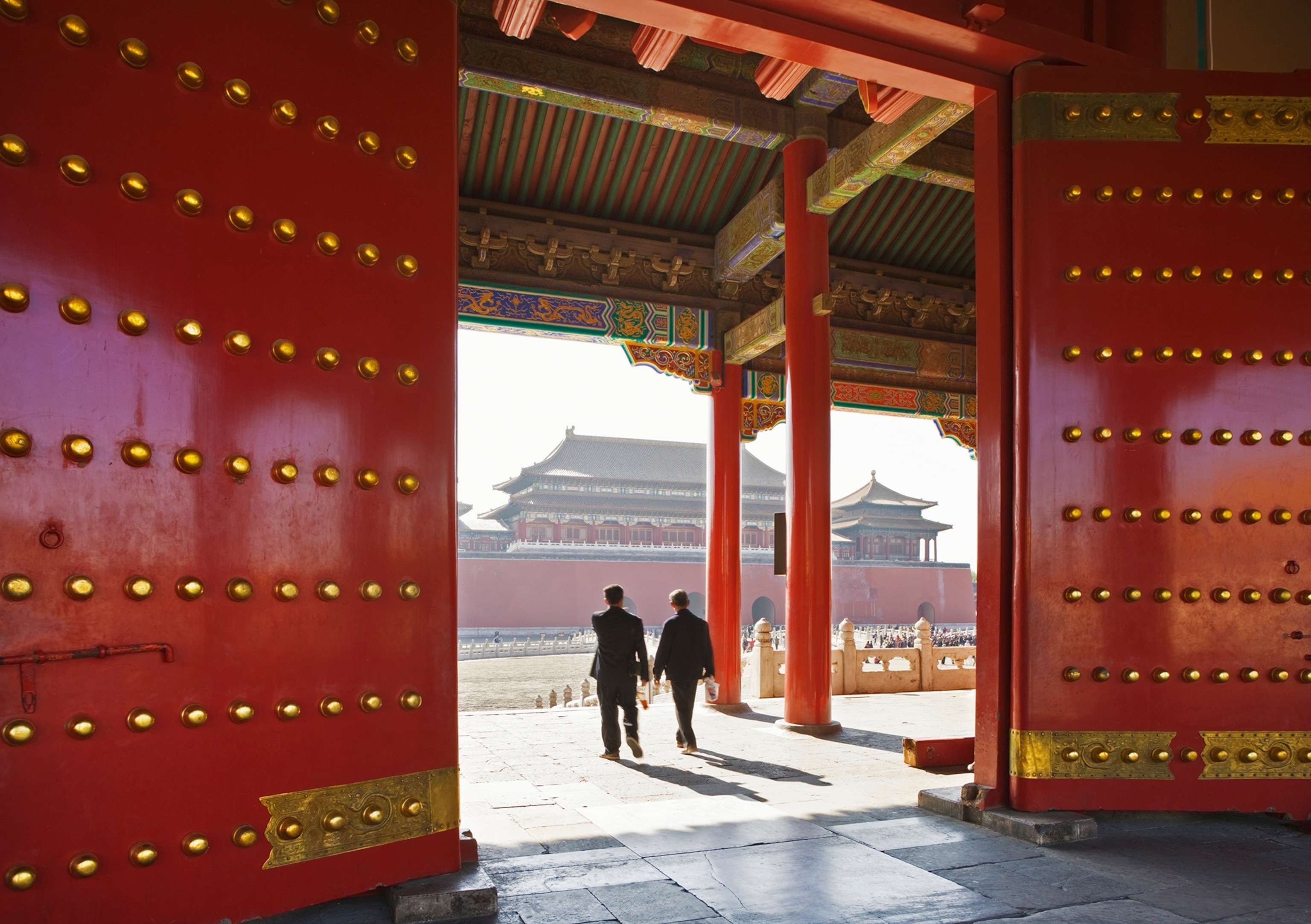 Two men walk through a gatehouse in the Forbidden City.
