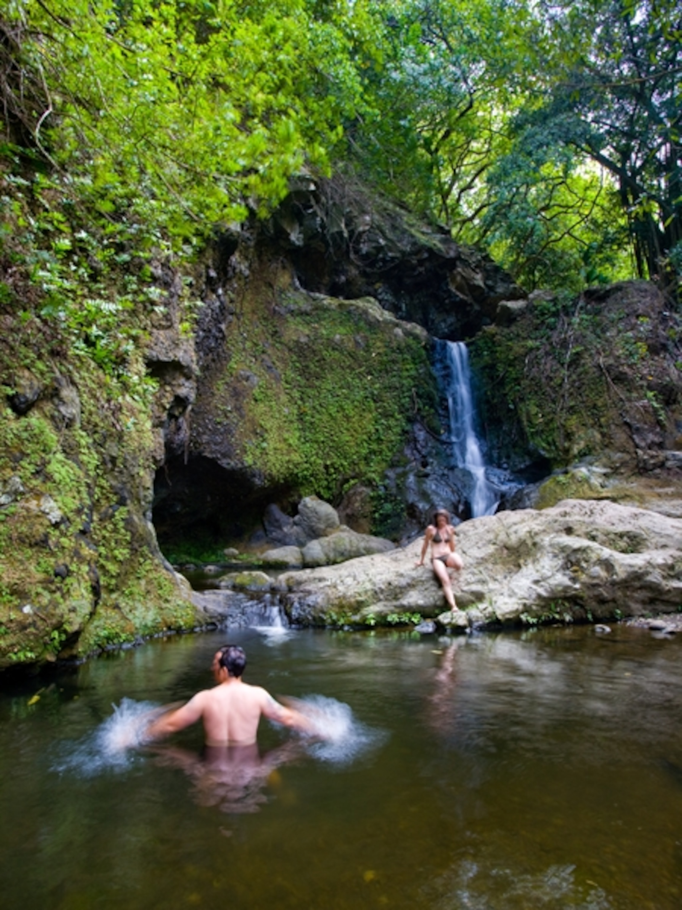 Couple splashes in Upper Makamaka'ole Falls, Maui, Hawaii