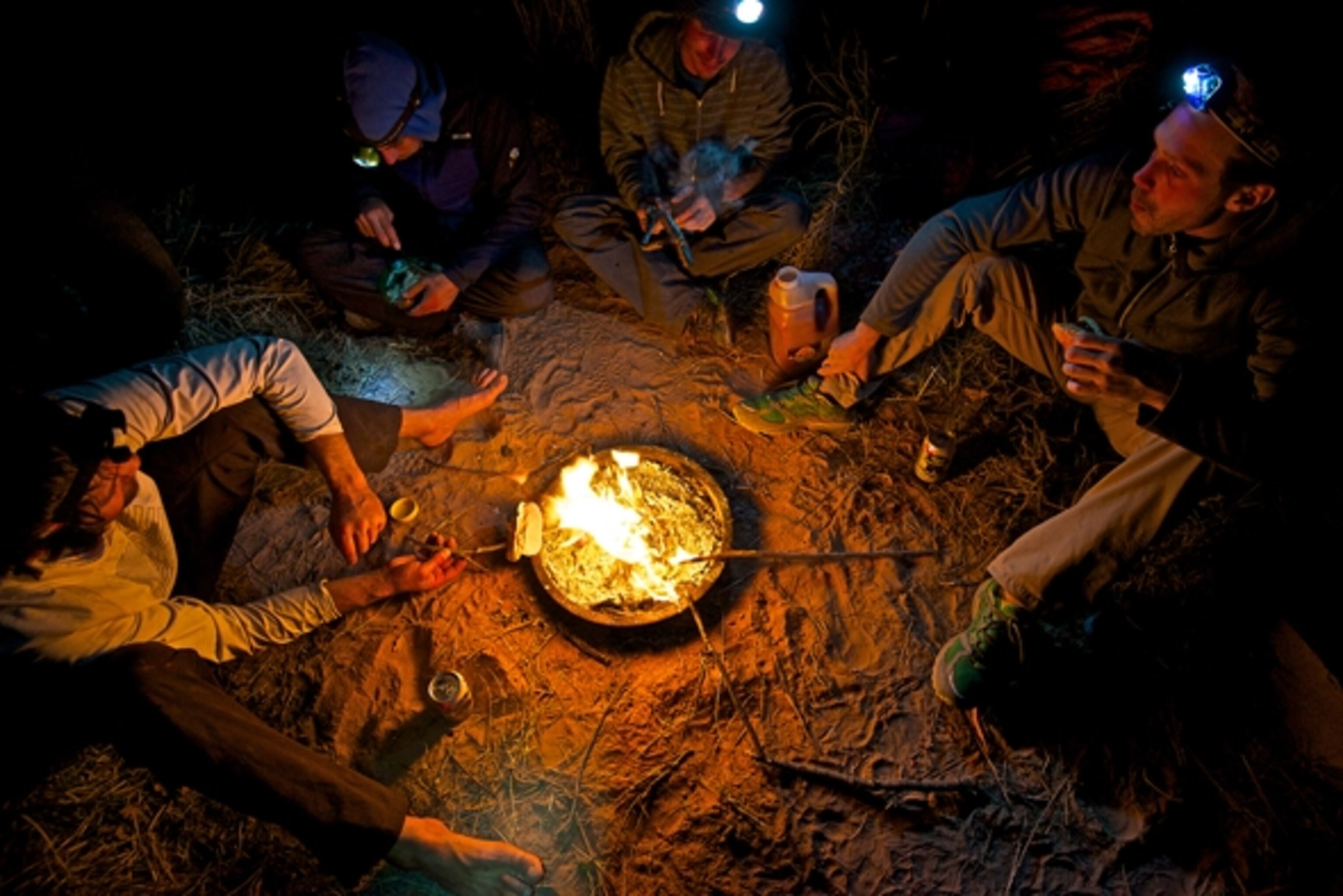 Renan Ozturk, Alex Honnold, Daniel Woods, and Matt Segal roast hotdogs at camp after a long day of climbing in Labyrinth Canyon, UT. Photograph by Celin Serbo