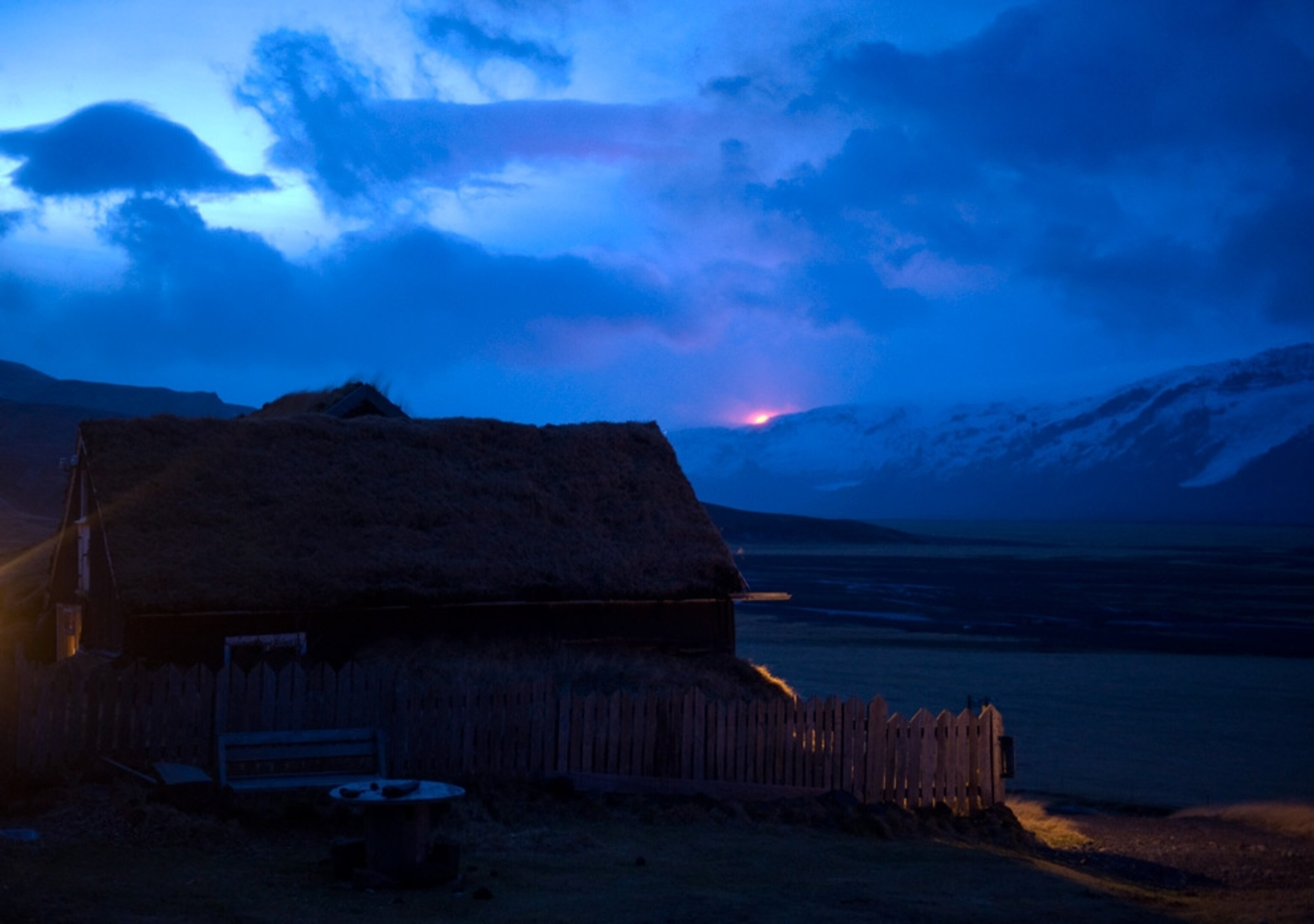 house as Iceland volcano erupts in the distance