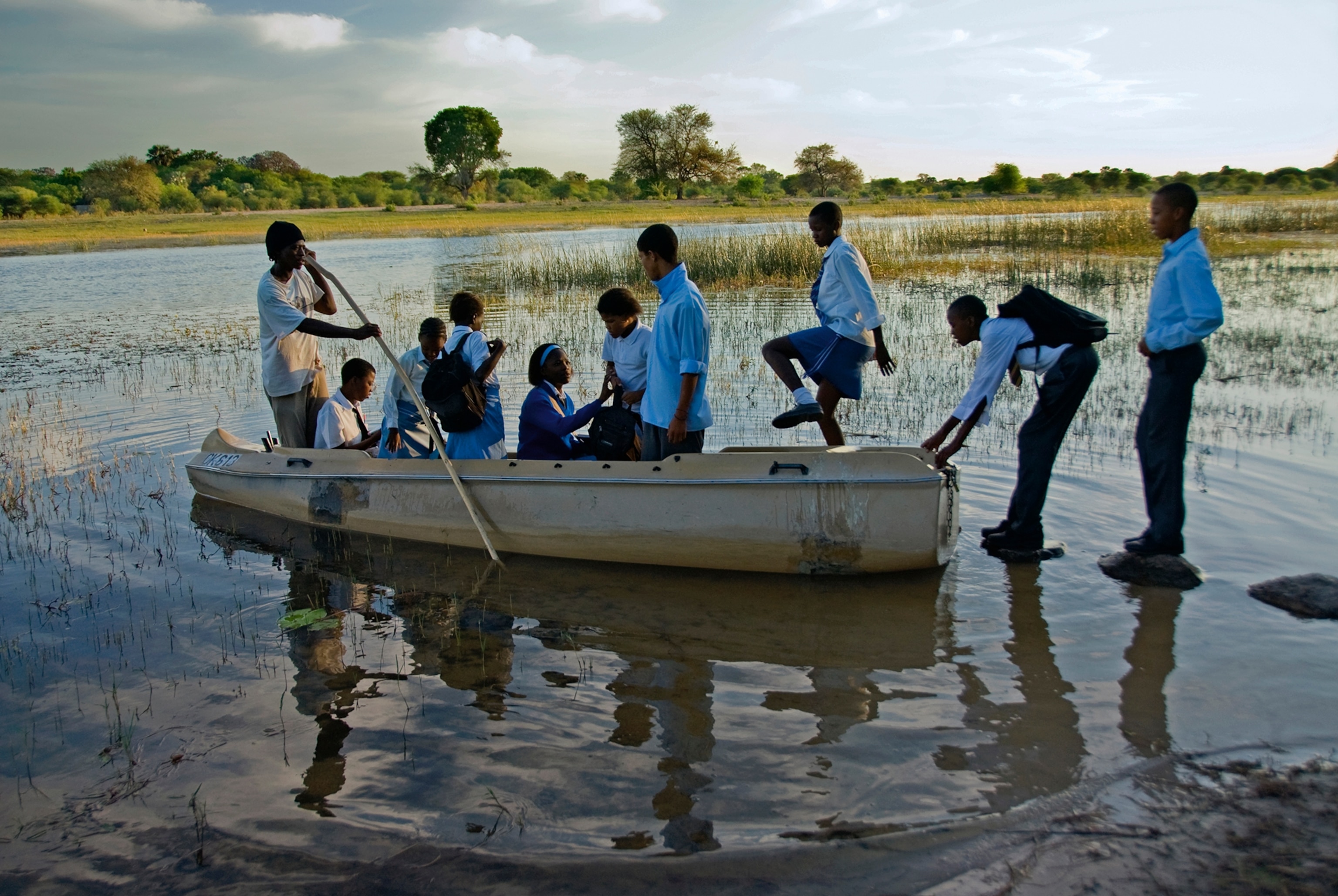 Children cross a river on their way to school in the rainy season.