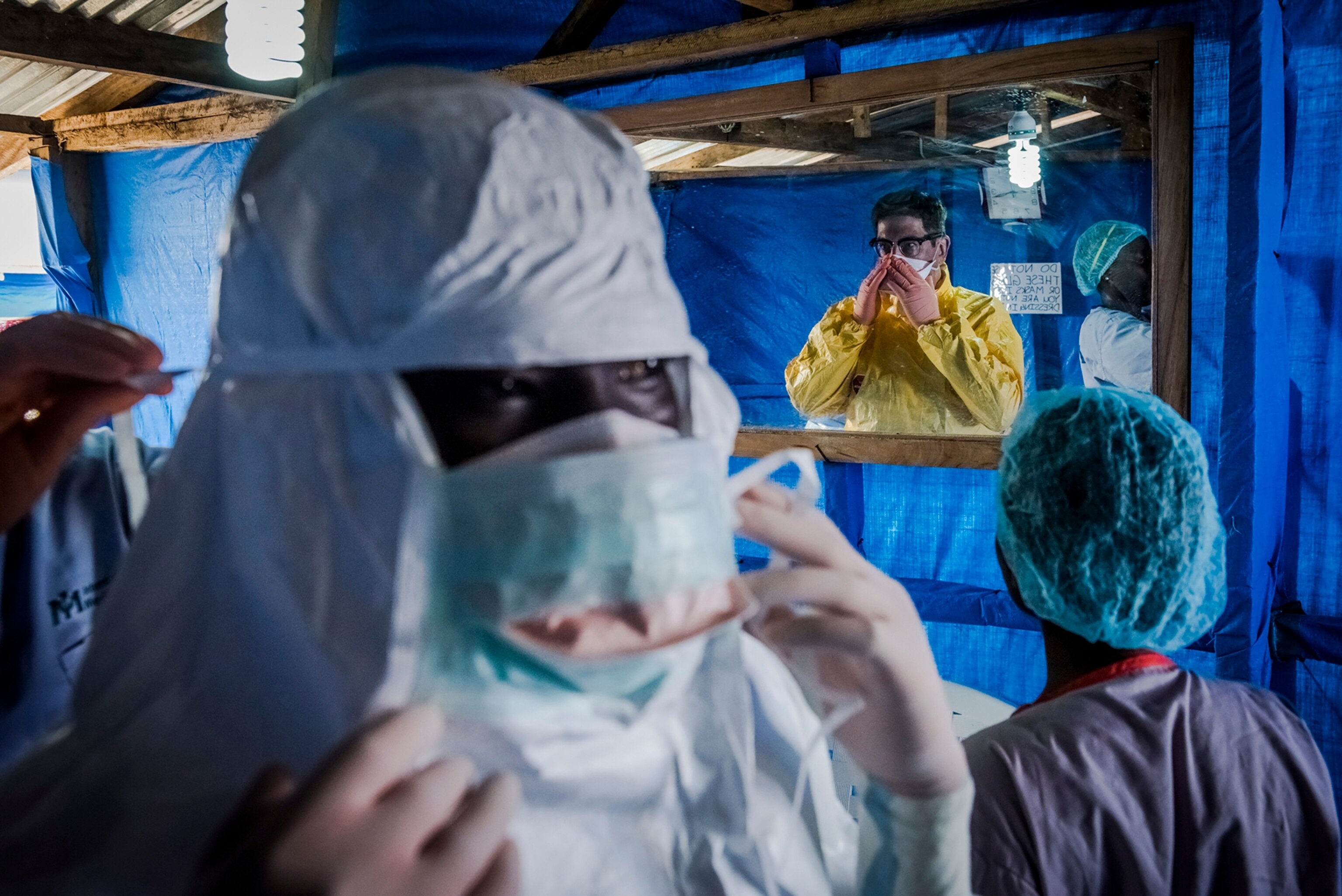 Dr. Steven Hatch, second from right, and colleagues dress into protective clothing before a shift at a clinic run by the International Medical Corps in Suakoko, Liberia, Oct. 12, 2014.