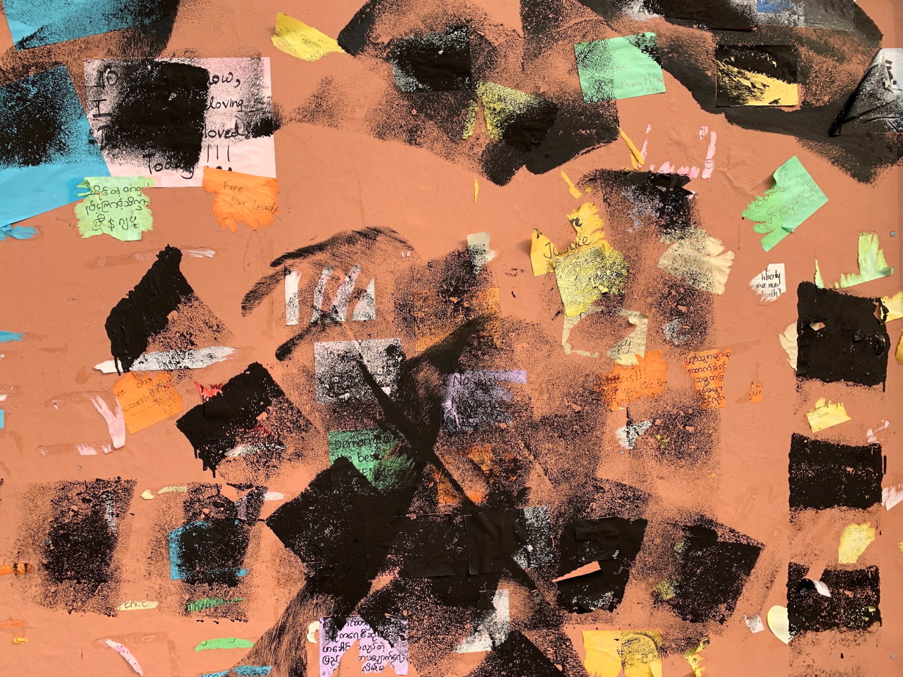 Notes on a wall are roughly censored by black paint