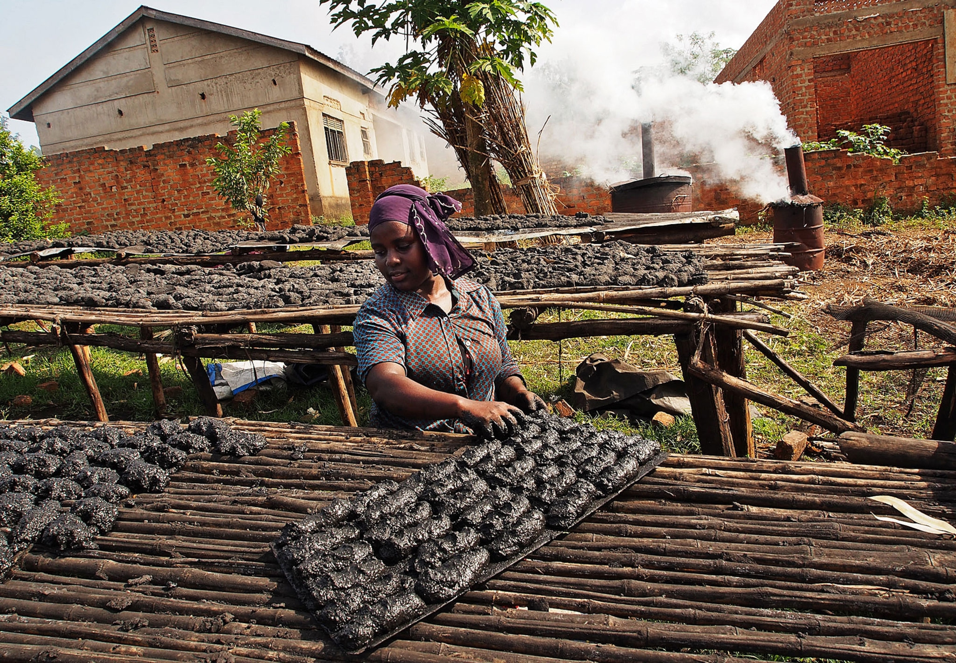 a worker laying out biochar to dry in Uganda
