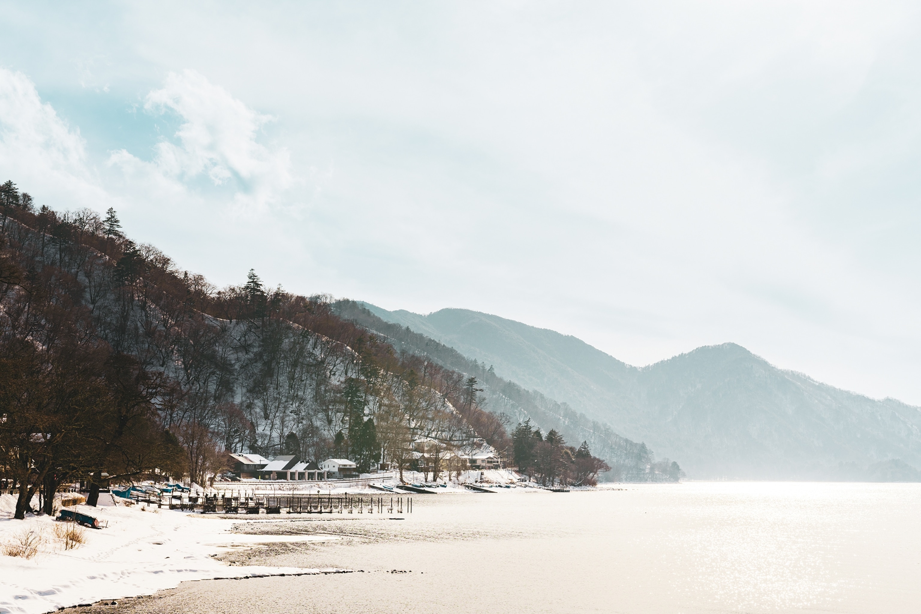 An icy, frozen-over lake landscape bordering hills.