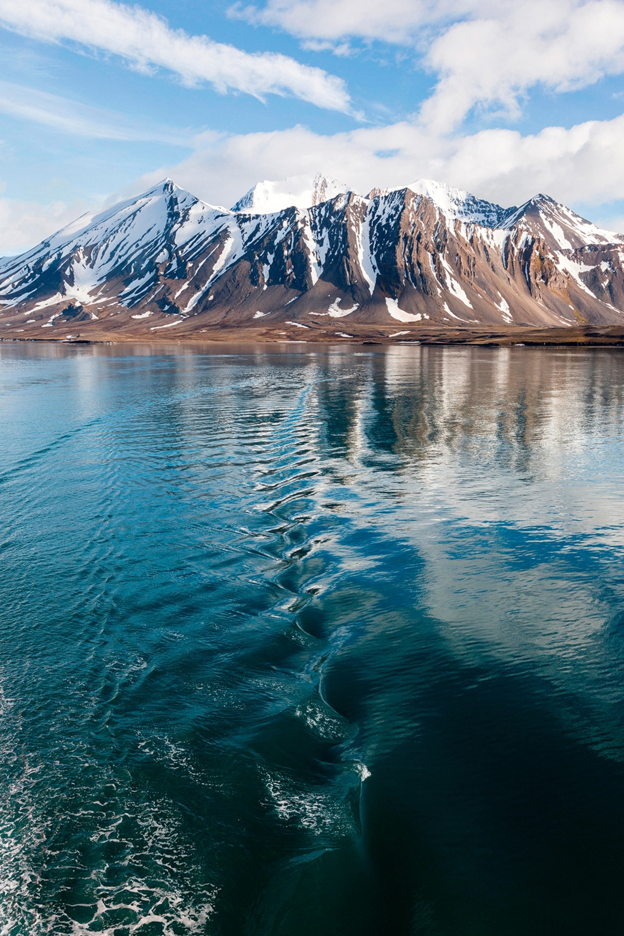 A snow-capped mountain scape with a clear rippling river in the front.