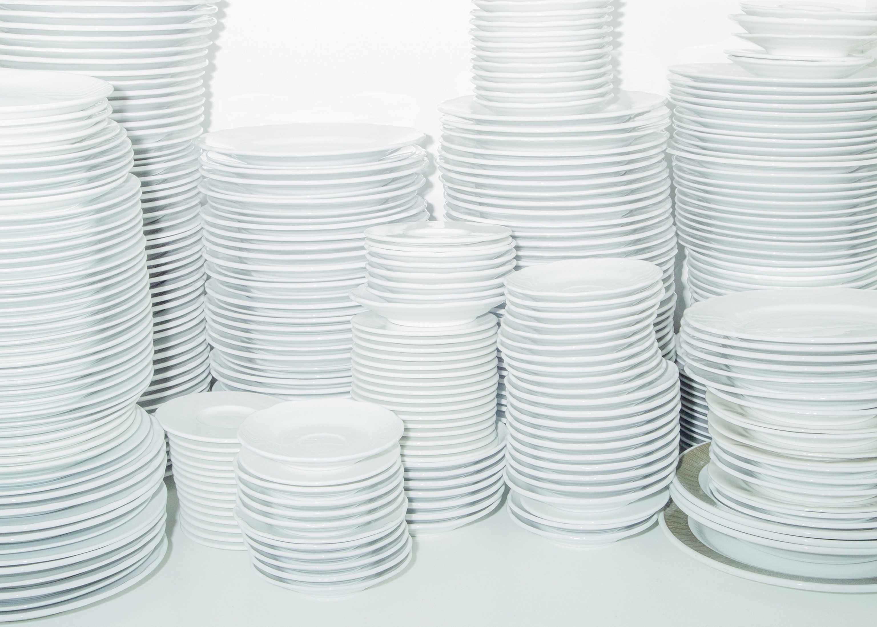 Stacks of white plates resting on a white table