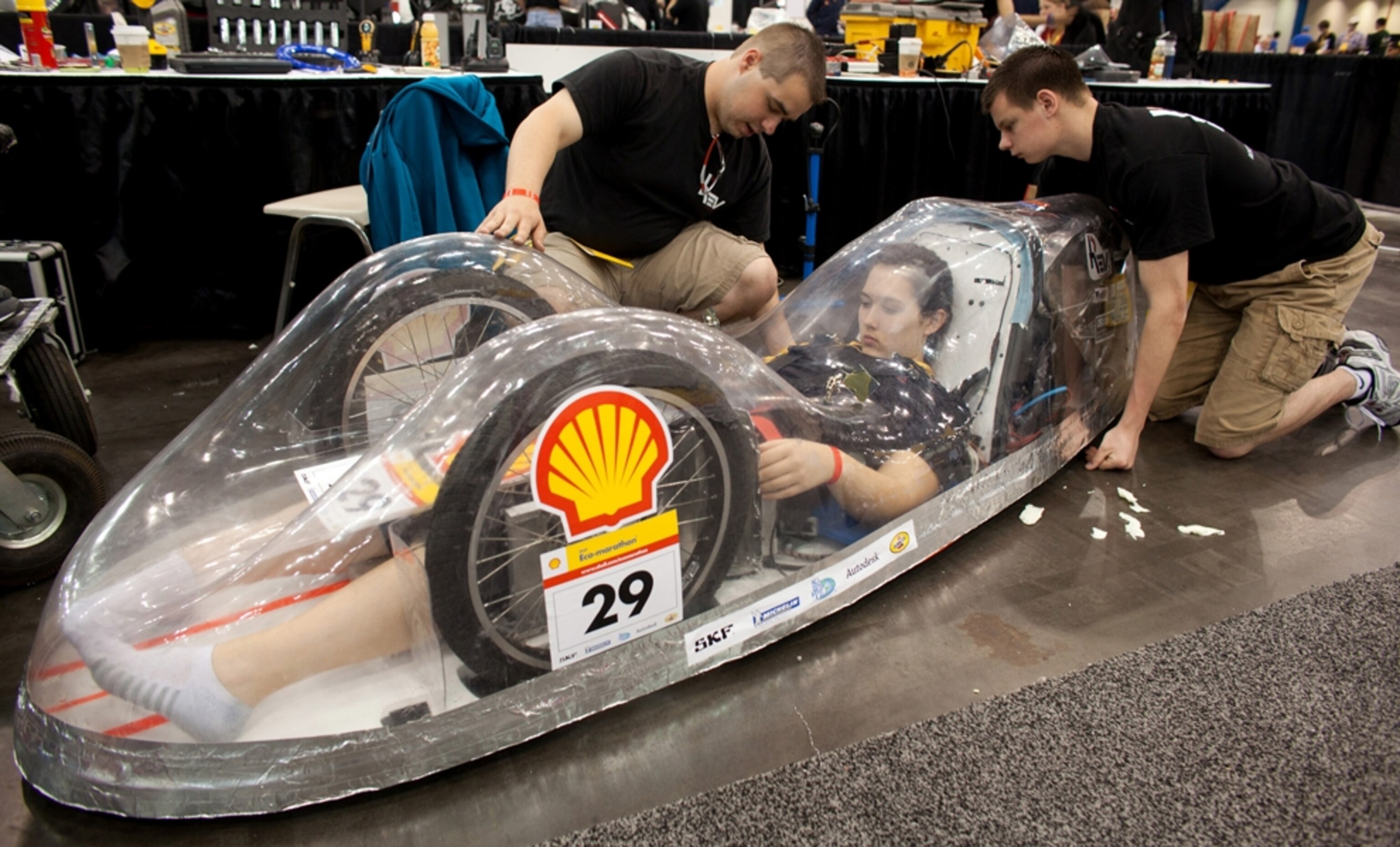 Driver reclines inside a car made of clear soda-bottle plastic