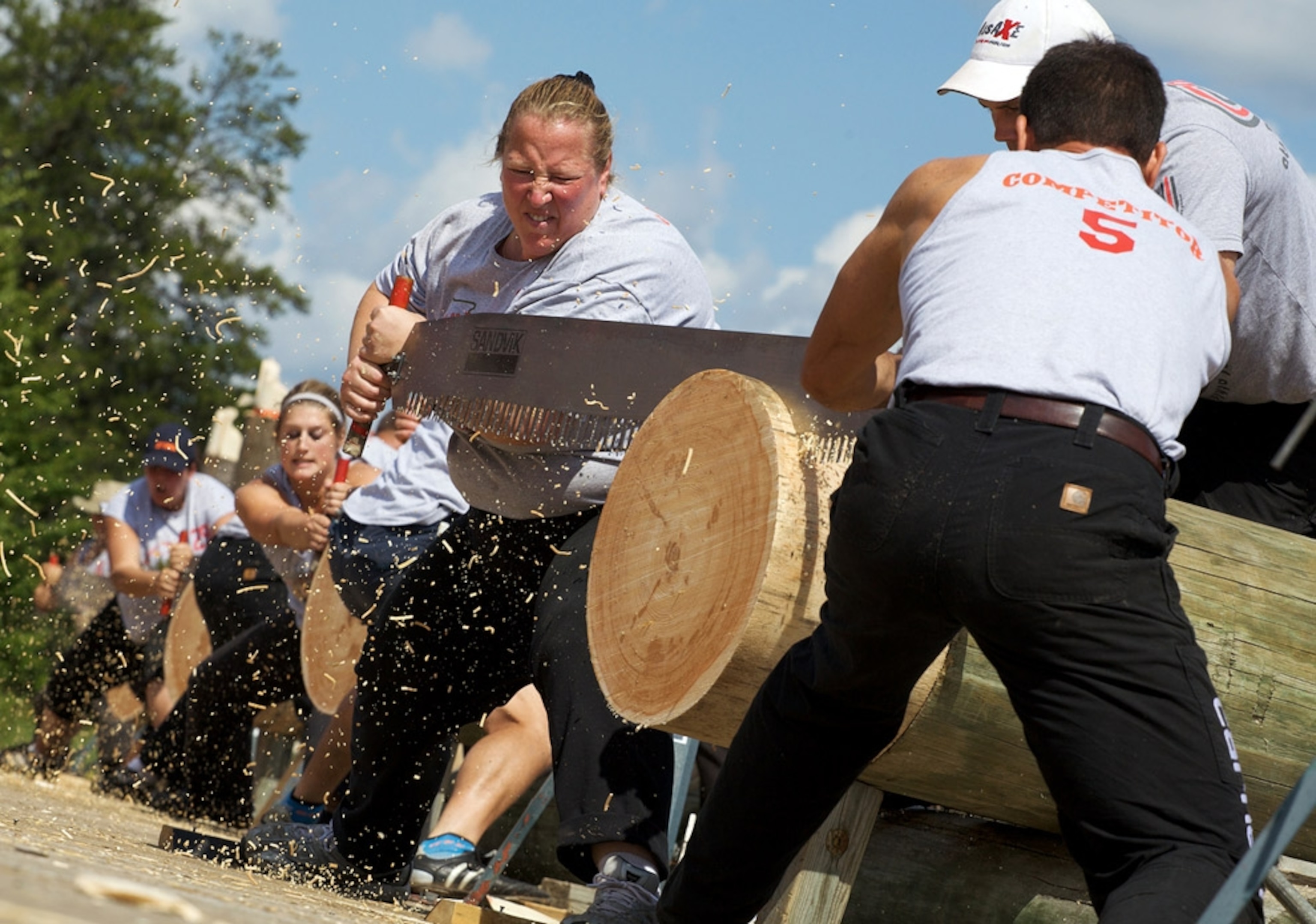 Men and women sawing logs