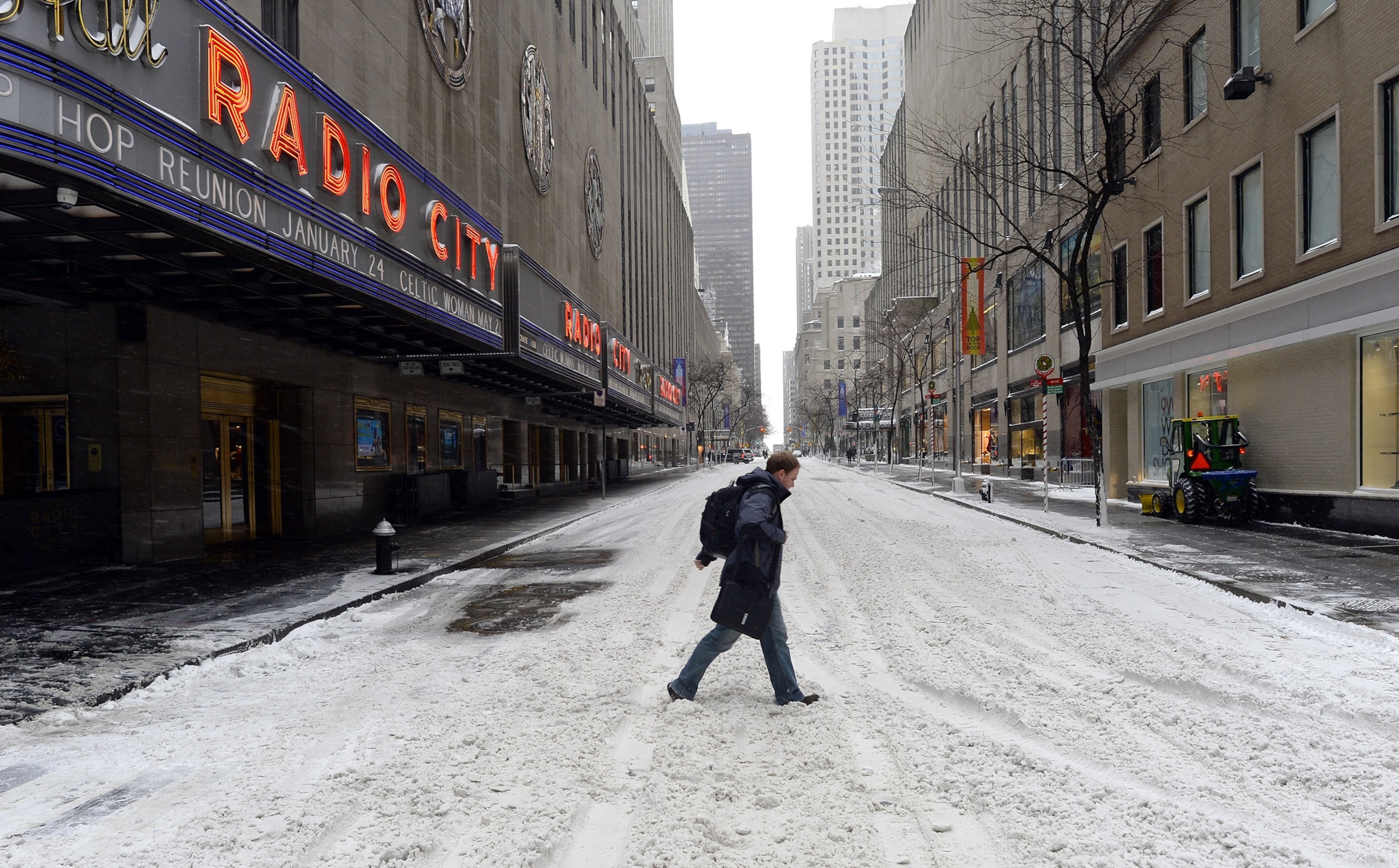 a man walking around Rockefeller Center in the snow.