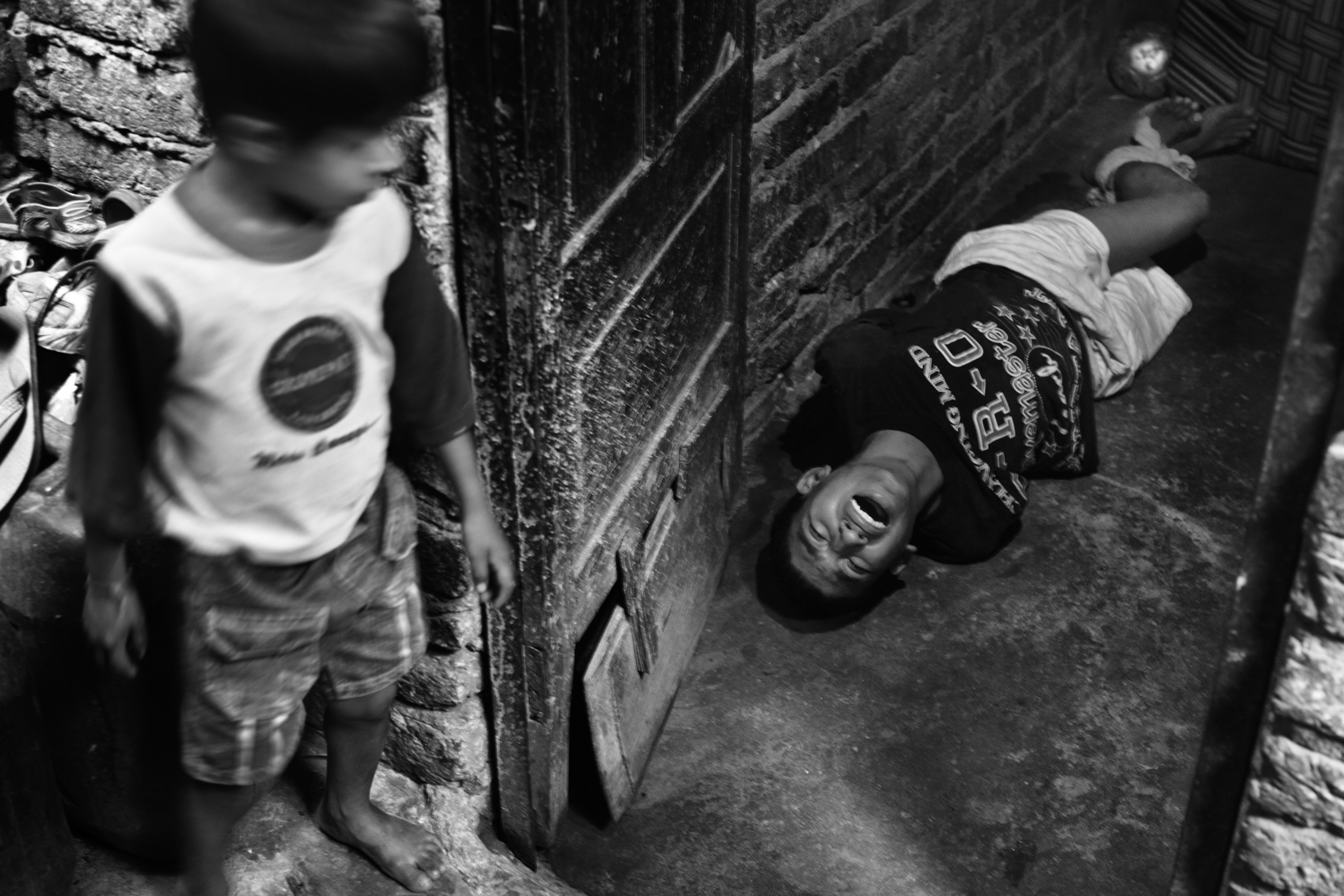 Wasim, 16, lies on the floor of the family’s living quarter, his hands and feet tied behind his back, while one of his younger brothers watches. His mother tied him up, with the help of a neighbor, after arguing about money for drugs. Wasim is the oldest of five children, living in one of the many slum settlements in Delhi.