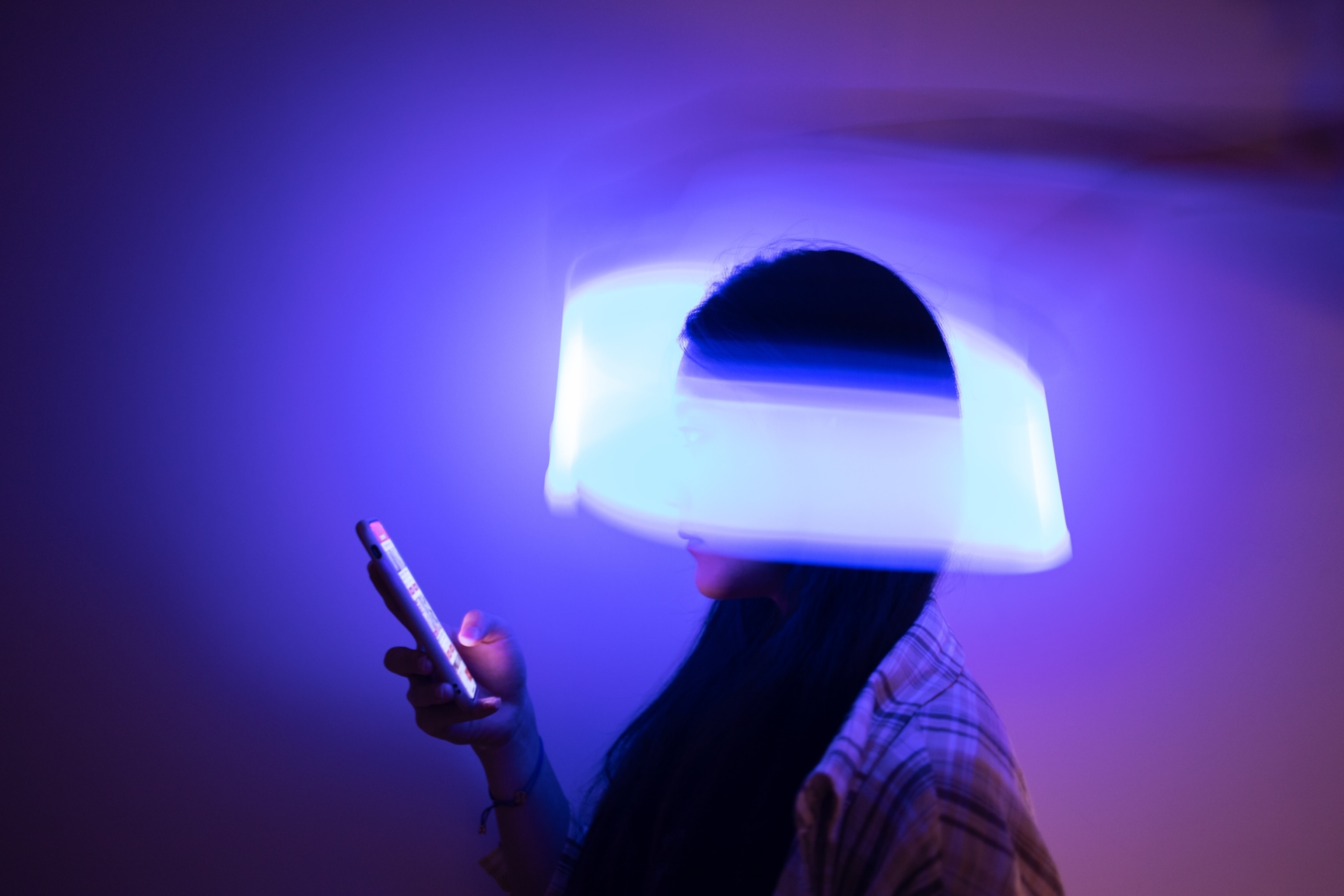 A woman looking at her phone with a swirl of light wrapping around her head