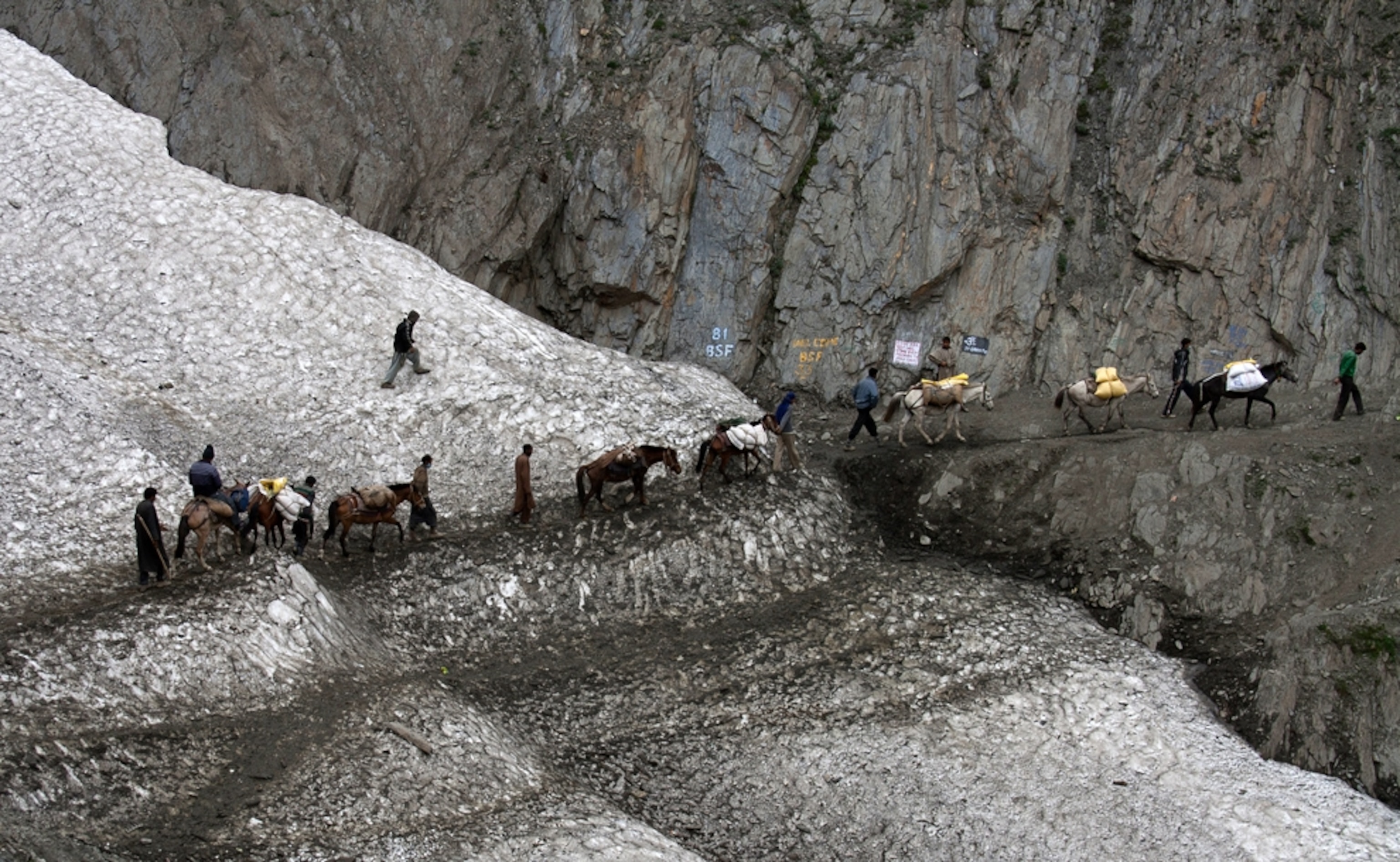 Kashmiri Bakarwals (nomads) and their ponies walk with Hindu pilgrims on a glacier at a base camp near the sacred Amarnath cave.