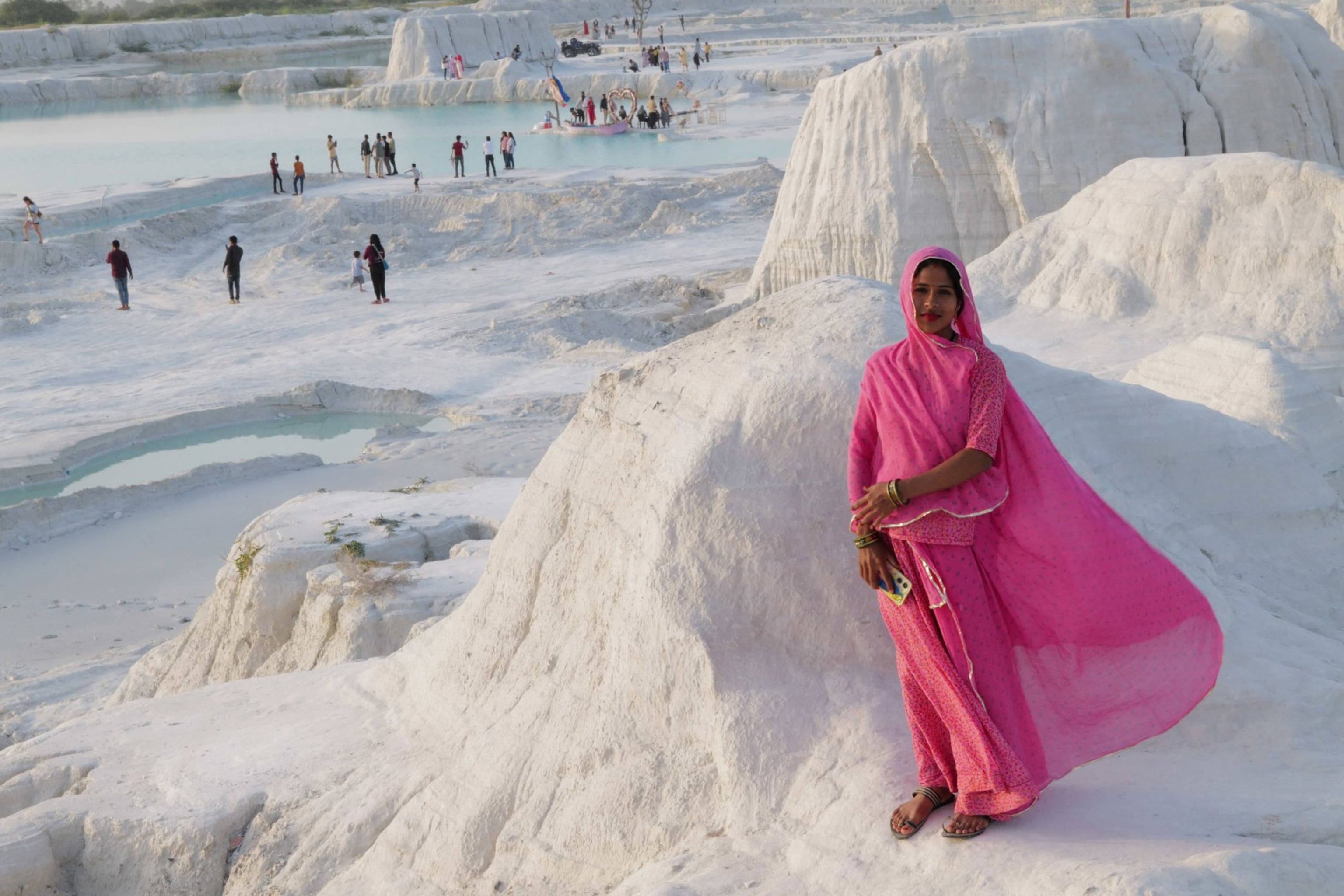 A girsl richly colored garment is blowing in the wind. You can see the various activities in the background.