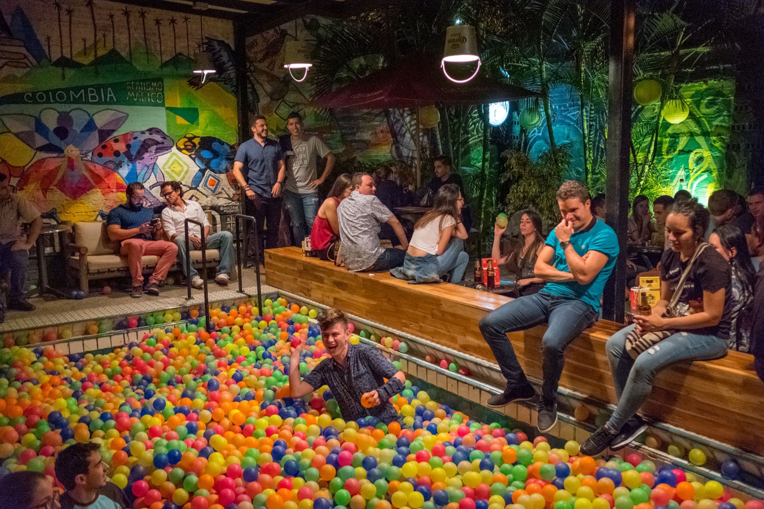 a pit full of colorful plastic balls at a bar filled with people