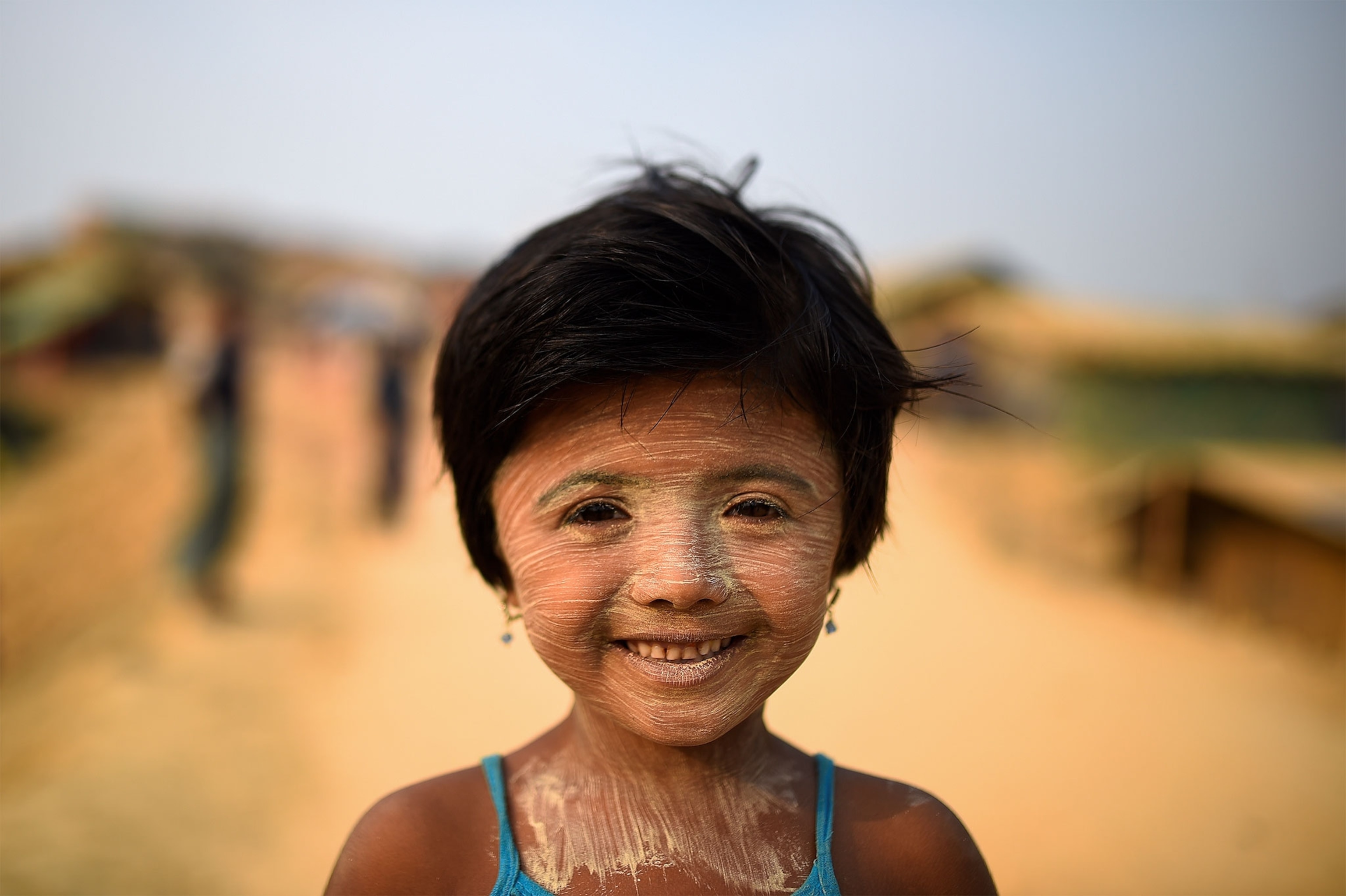 a Rohingya girl wearing paint on her face to protect her from the sun