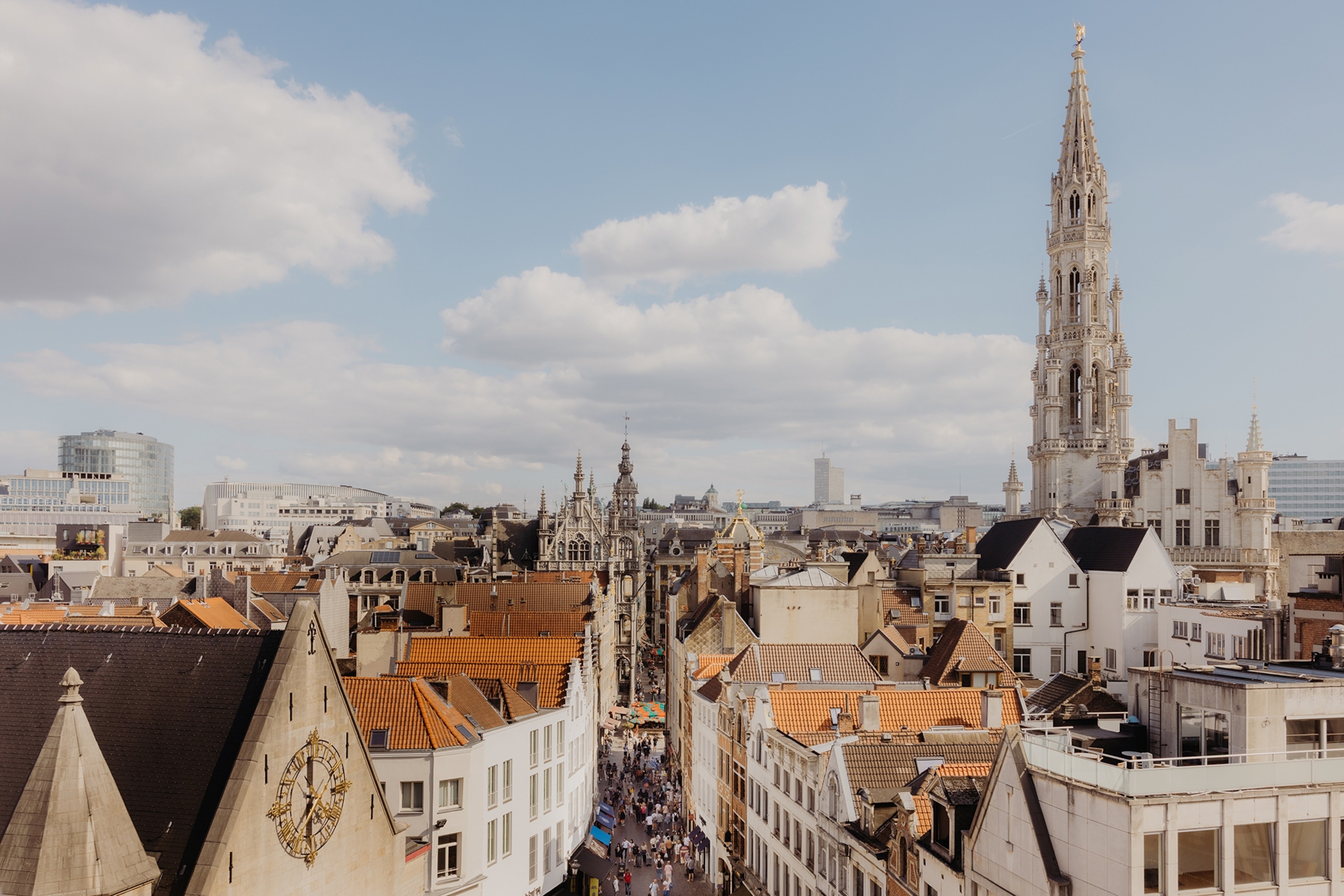 A busy, city skyline with a mix of modern and historical buildings, featuring a sky-reaching church steeple.