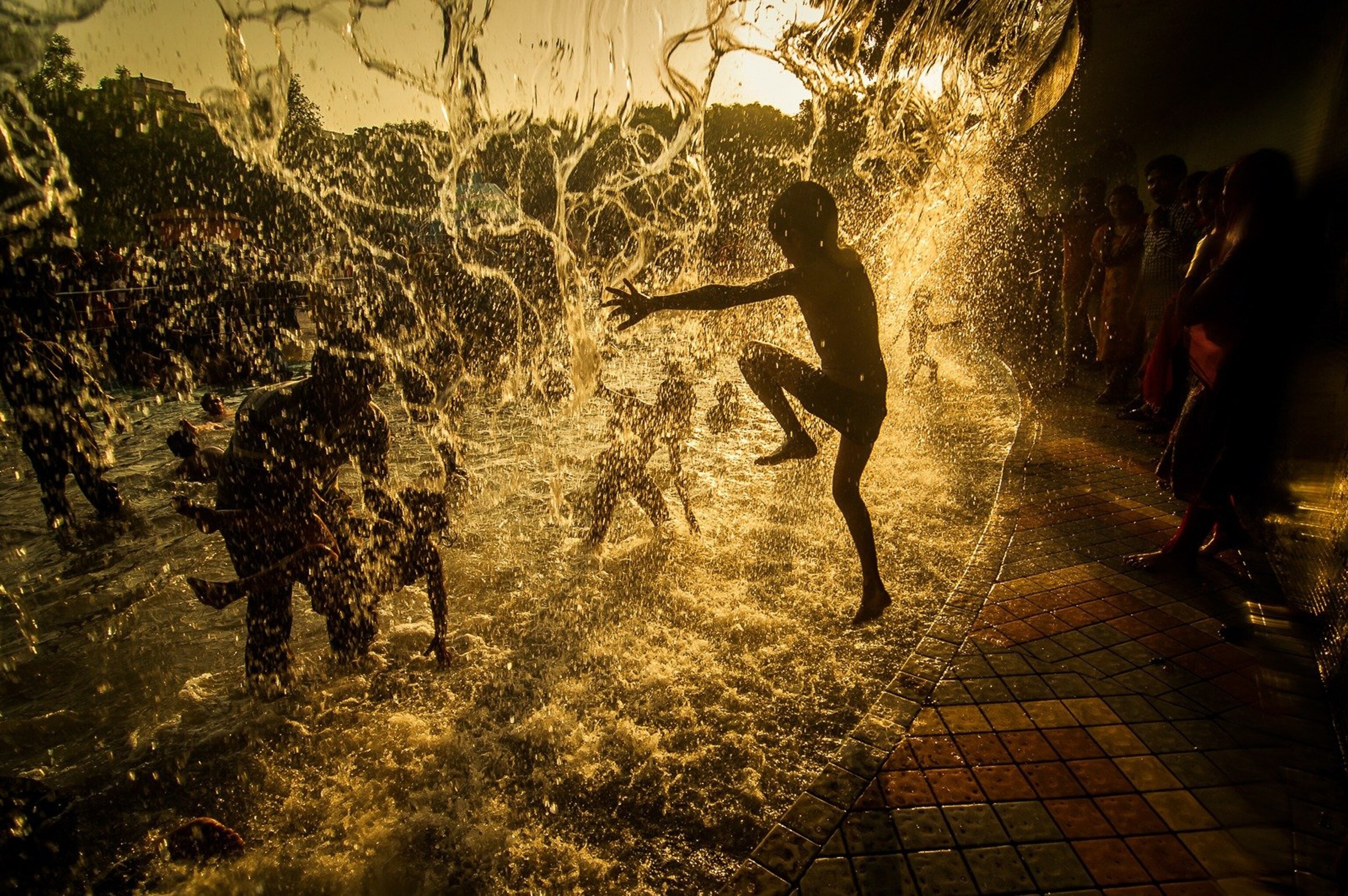 children playing in a fountain, India