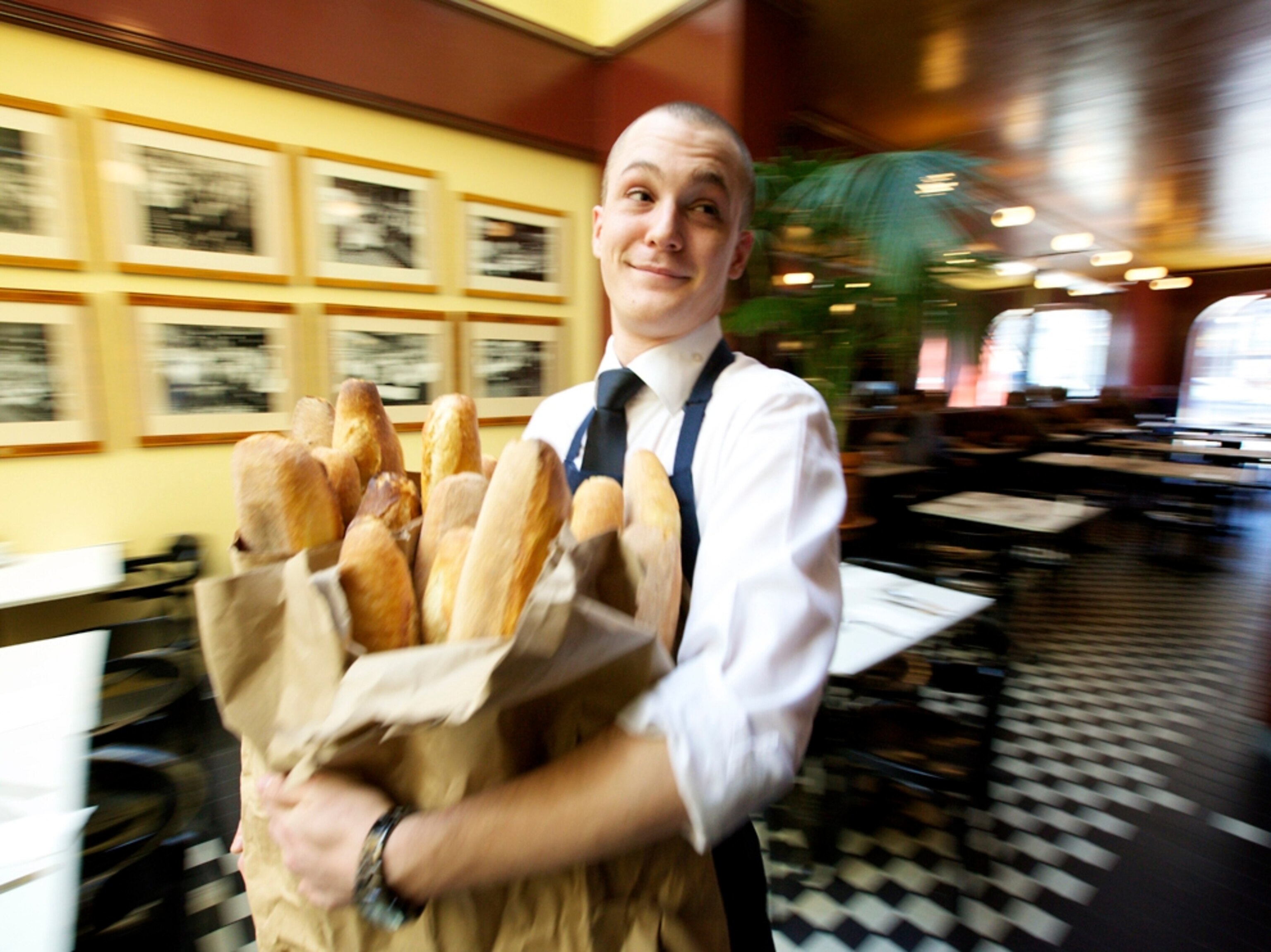 A waiter carrying baguettes