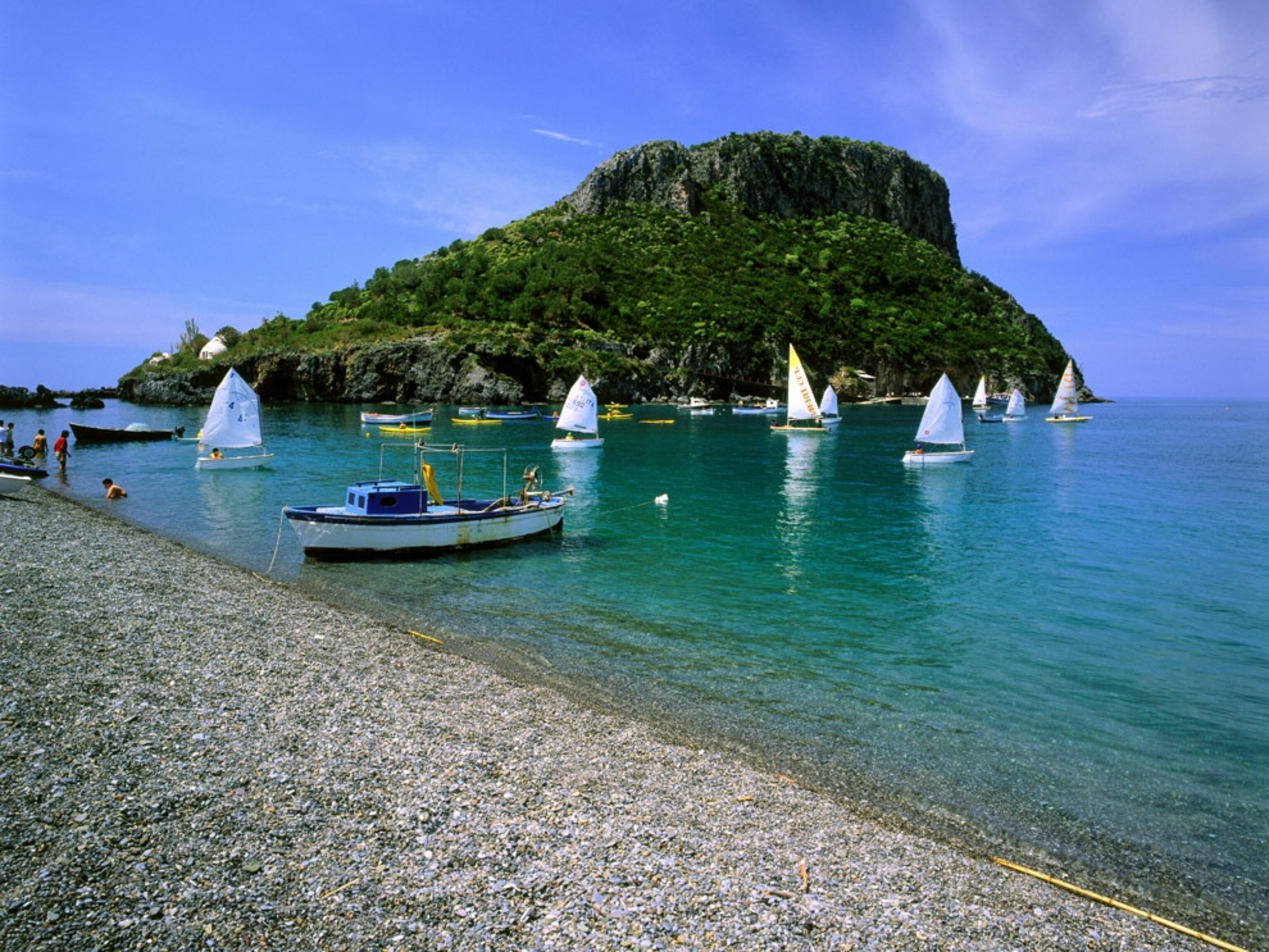 Sailboats circling a rocky island