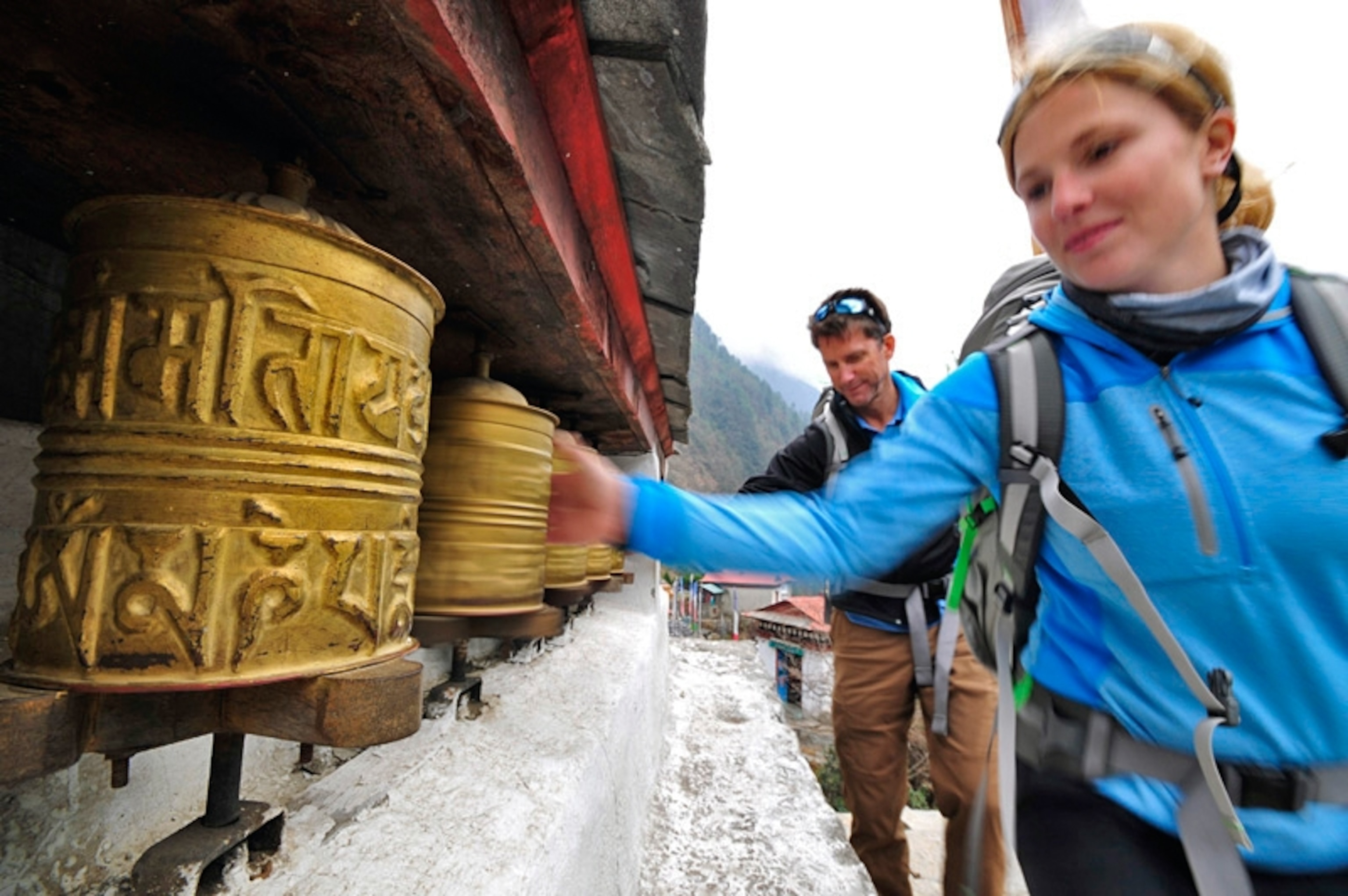 Melissa Arnot and Peter Whittaker spin Tibetan Buddhist prayer wheels en route to Phakding