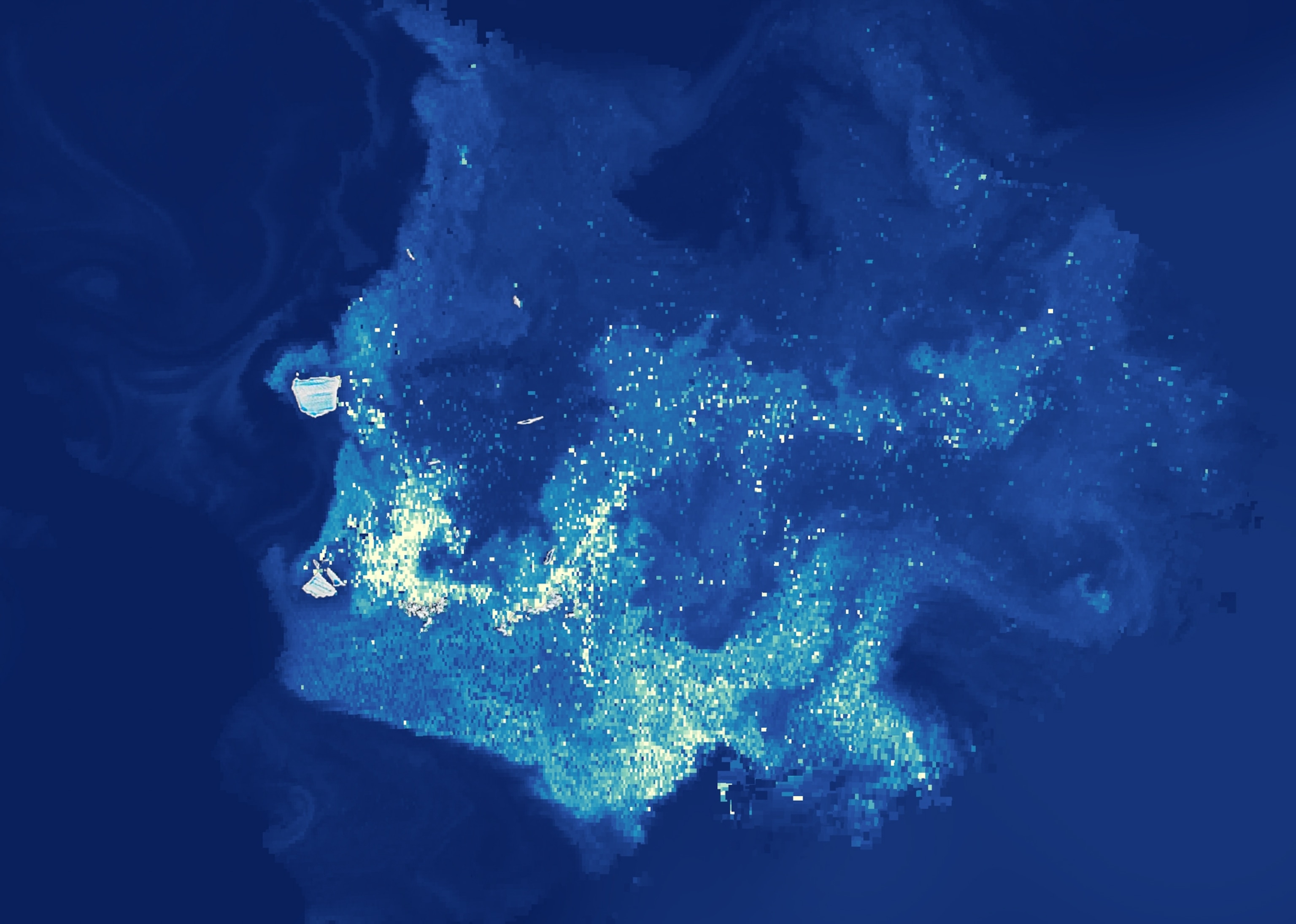 A color enhanced aerial view of an iceberg surrounded by a dense cluster of bright, glowing dots representing blooms of algae