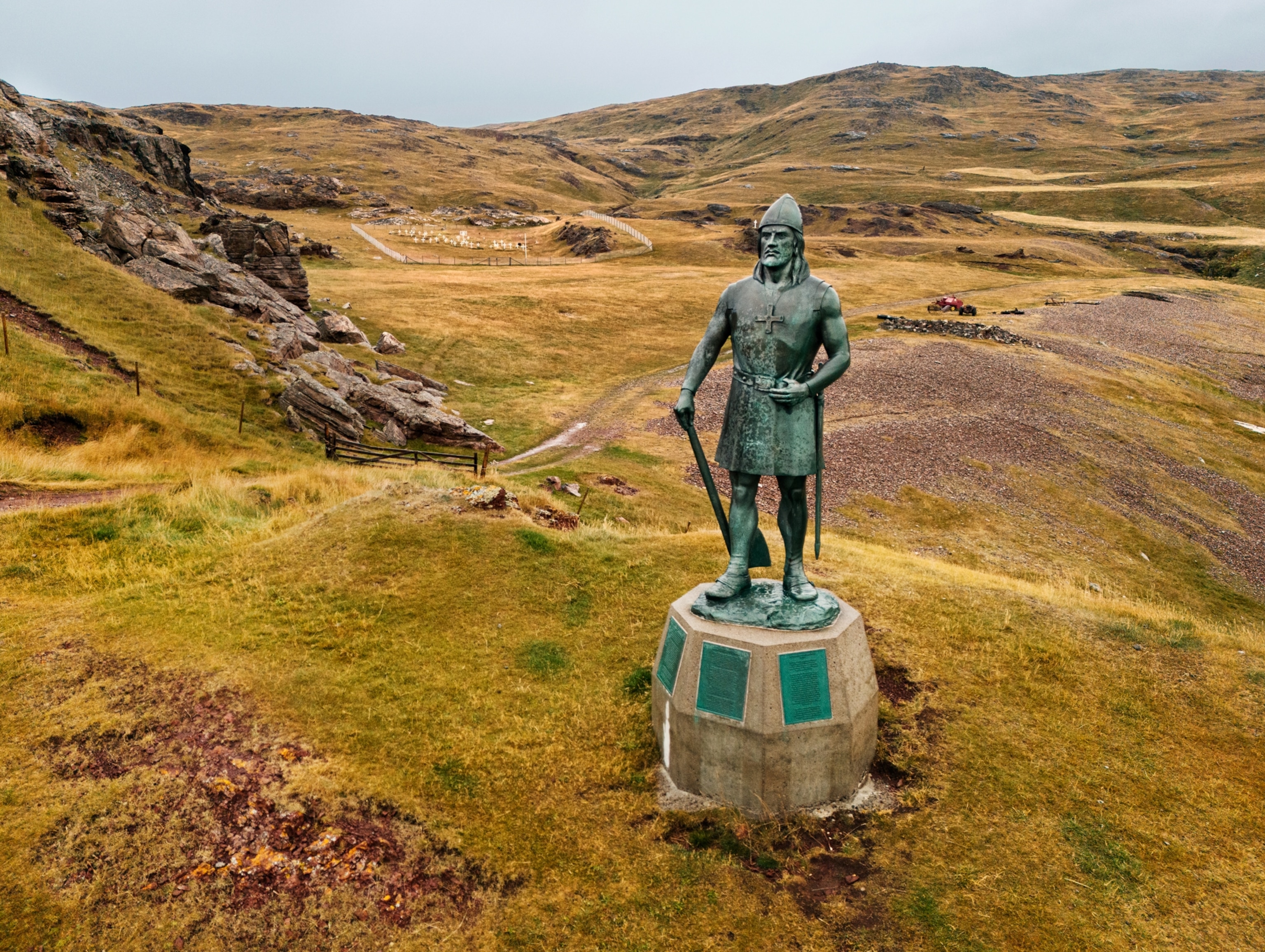 Bronze statue overlooking yellow rolling hills.