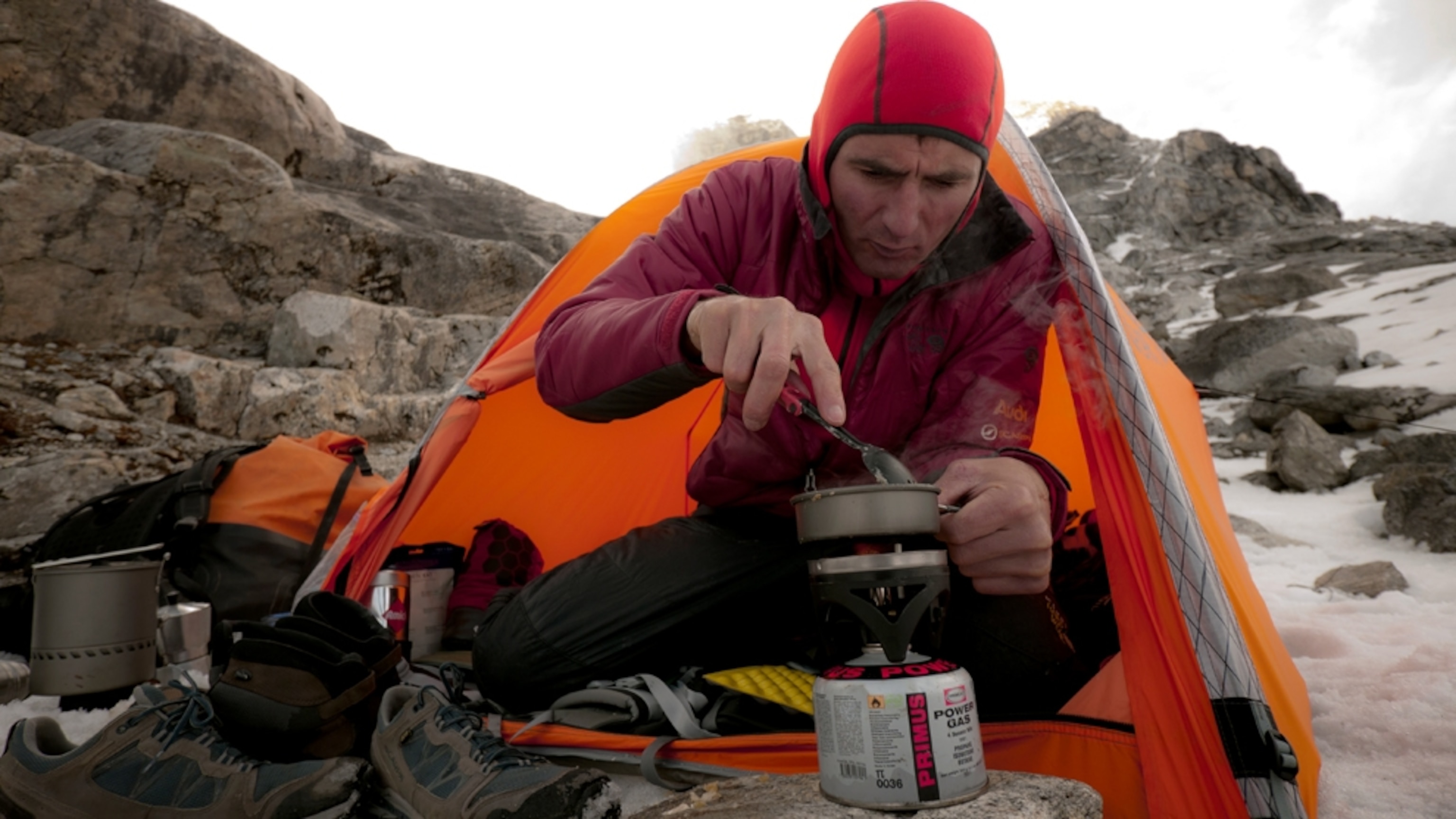 Alpine climber Ueli Steck prepares breakfast on a mountain