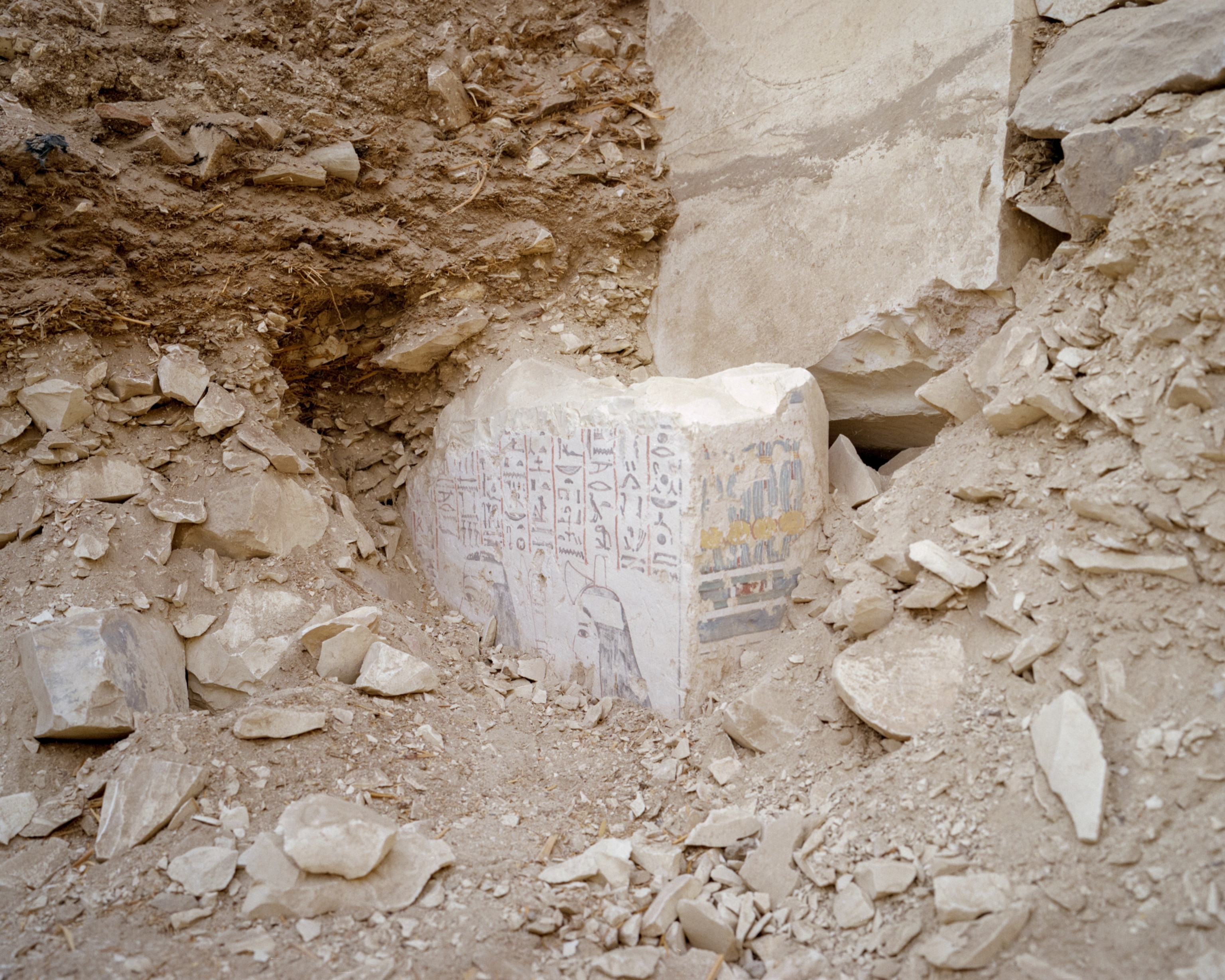 Decorated wall fragment protruding from the debris of a tomb.