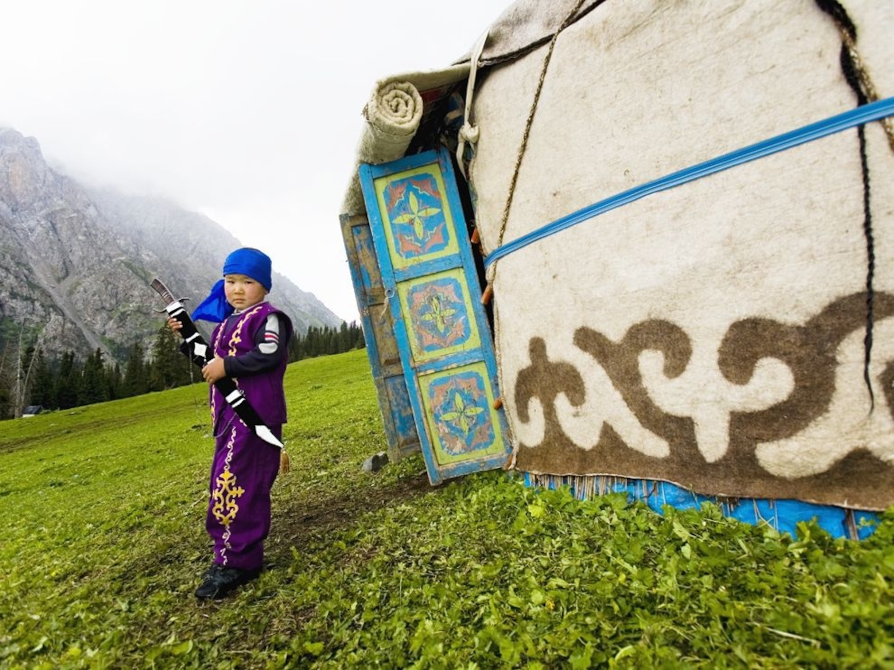 a boy standing by traditional Kyrgyzstan tent