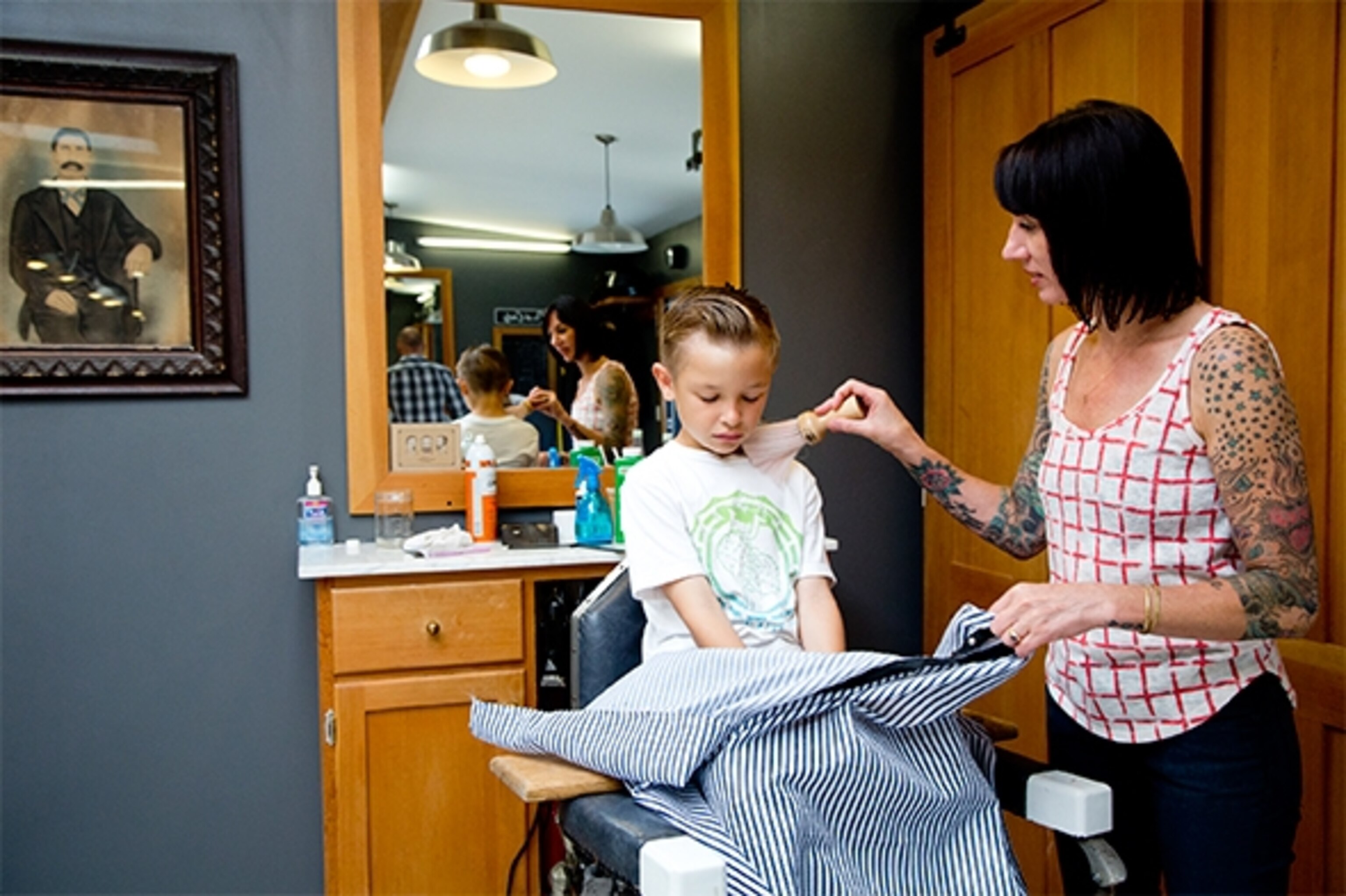 Lisa Monda tends to Alexander Seeley at the Temescal Alley Barbershop, known for its cool atmosphere, slick and dapper haircuts, and old-school razor shaves.  (Photograph by Catherine Karnow)