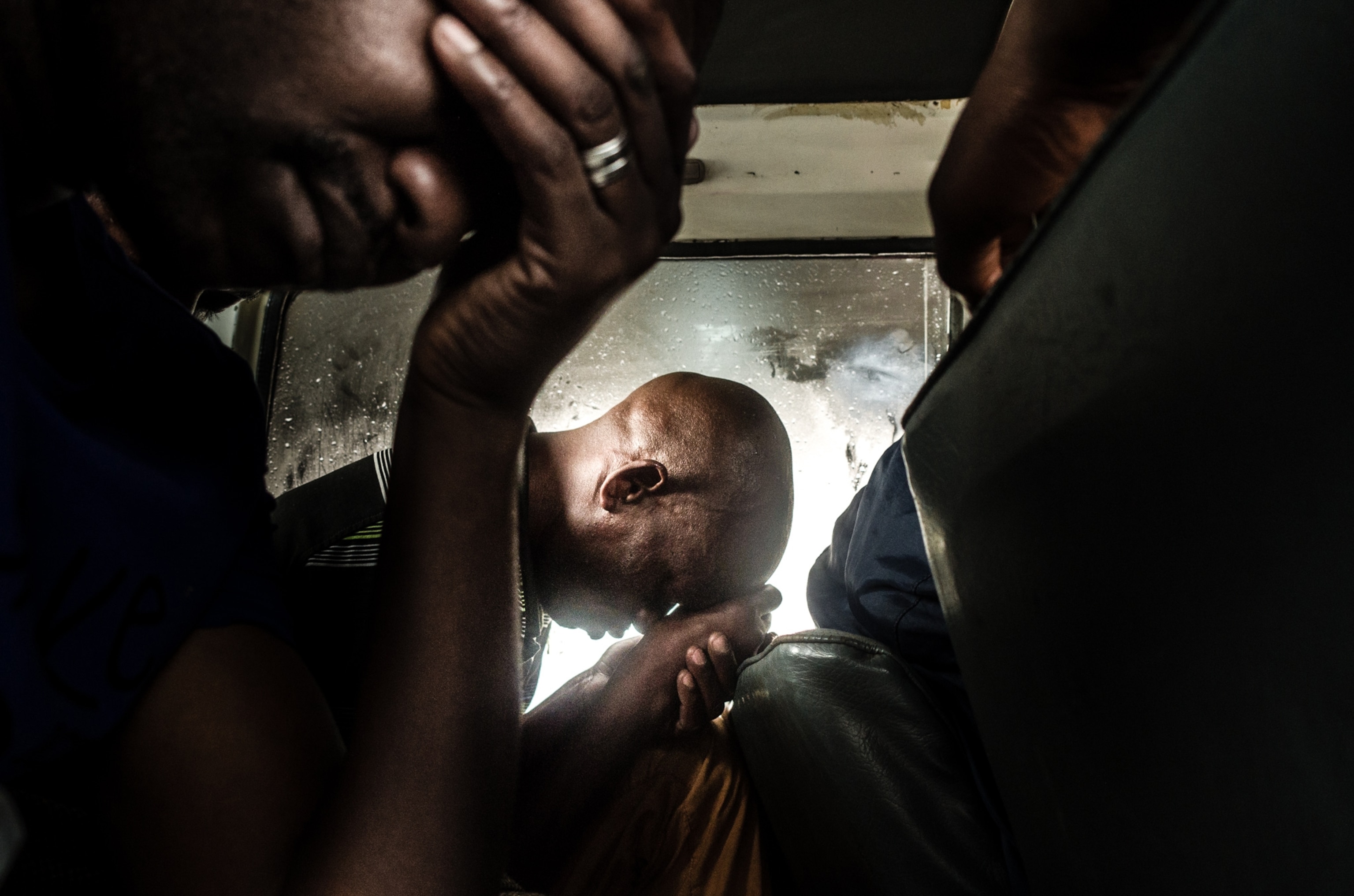 two men holding their heads in their hands while riding on the train.