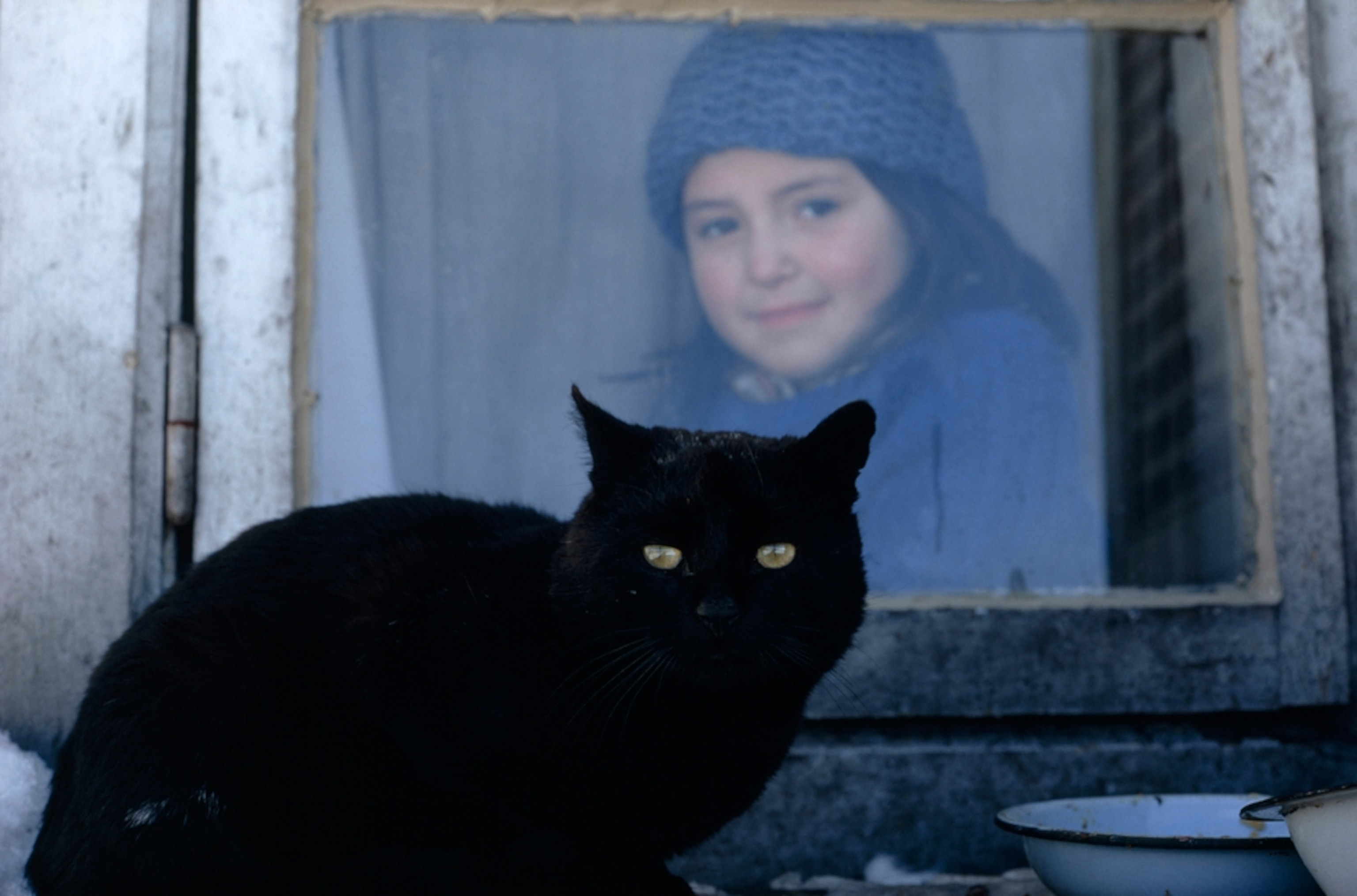a girl in a window and a black cat on ledge, Chile